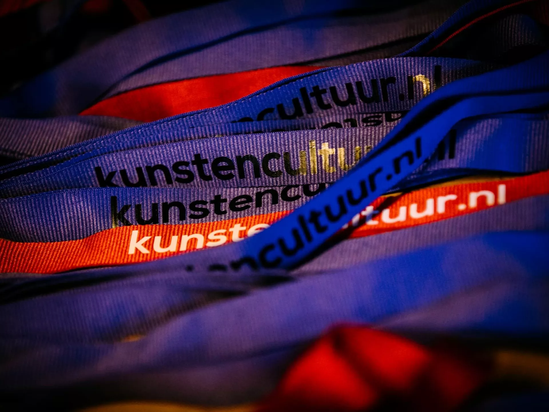 Stapel gekleurde polsbandjes met tekst "kunstencultuur.nl".