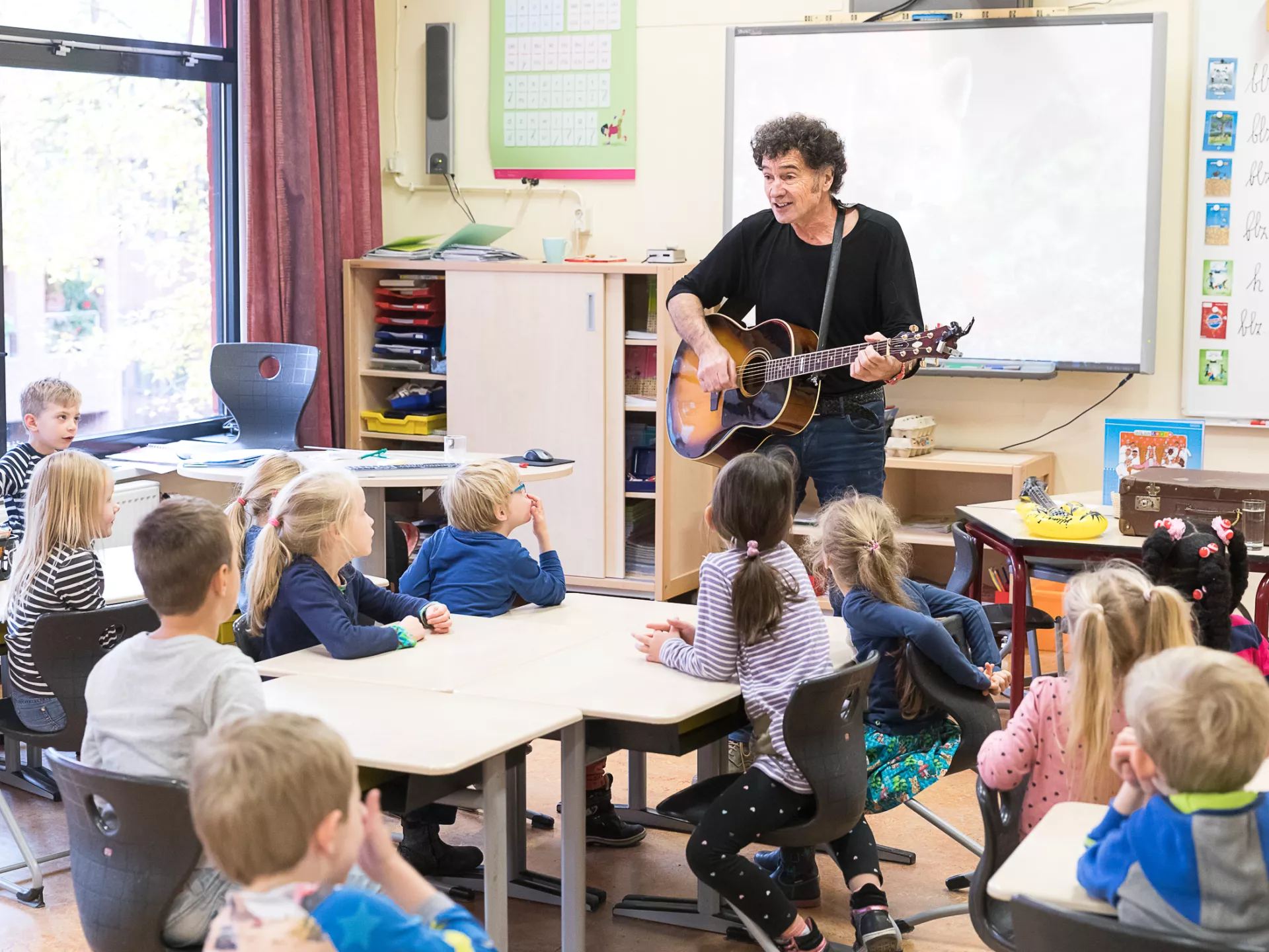 Culturele 50 - zingen in canon - man met een gitaar voor een klas leerlingen die zingen