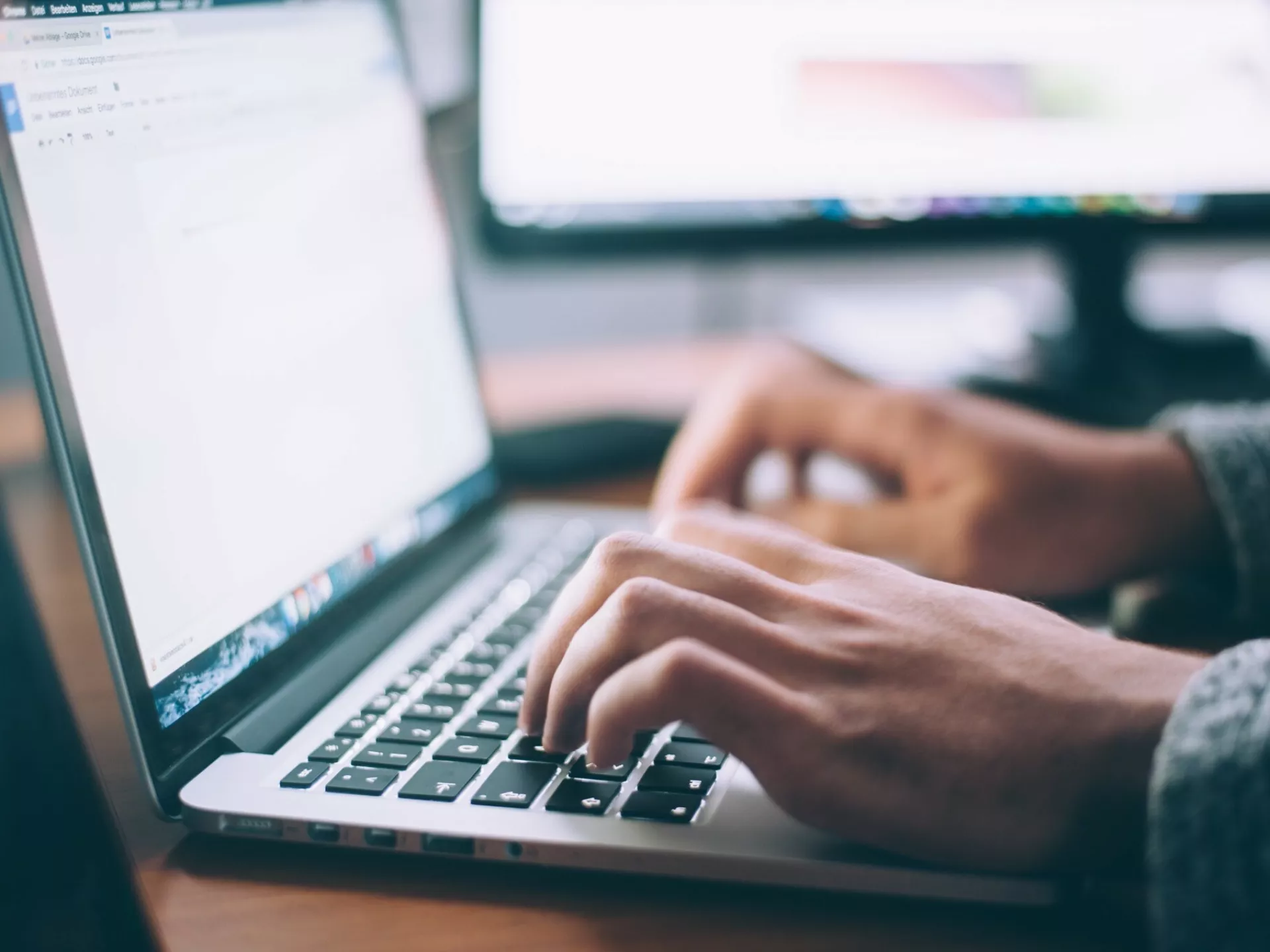Laptop met twee handen van persoon die typt