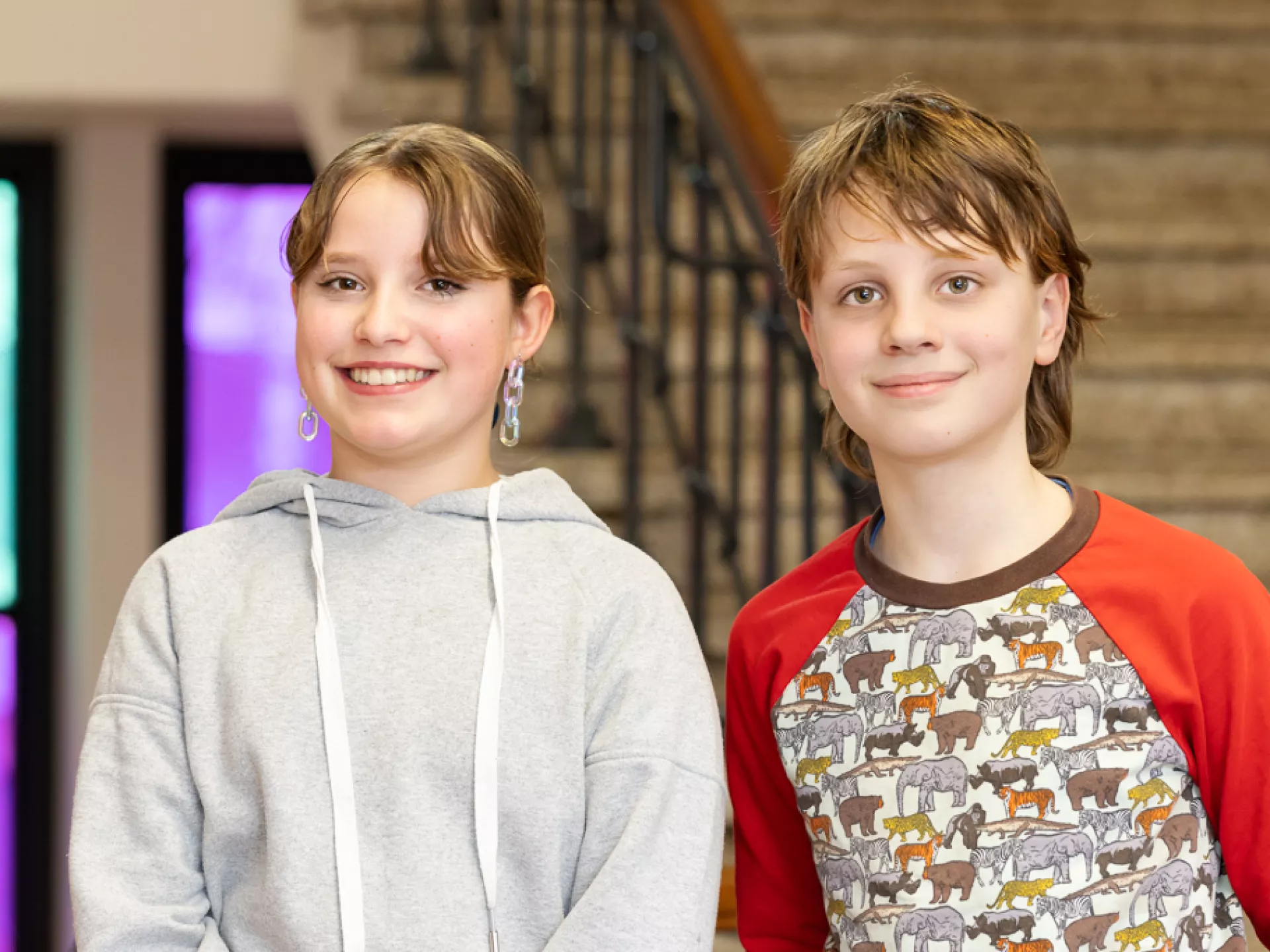 Twee lachende kinderen poseren voor een trap.