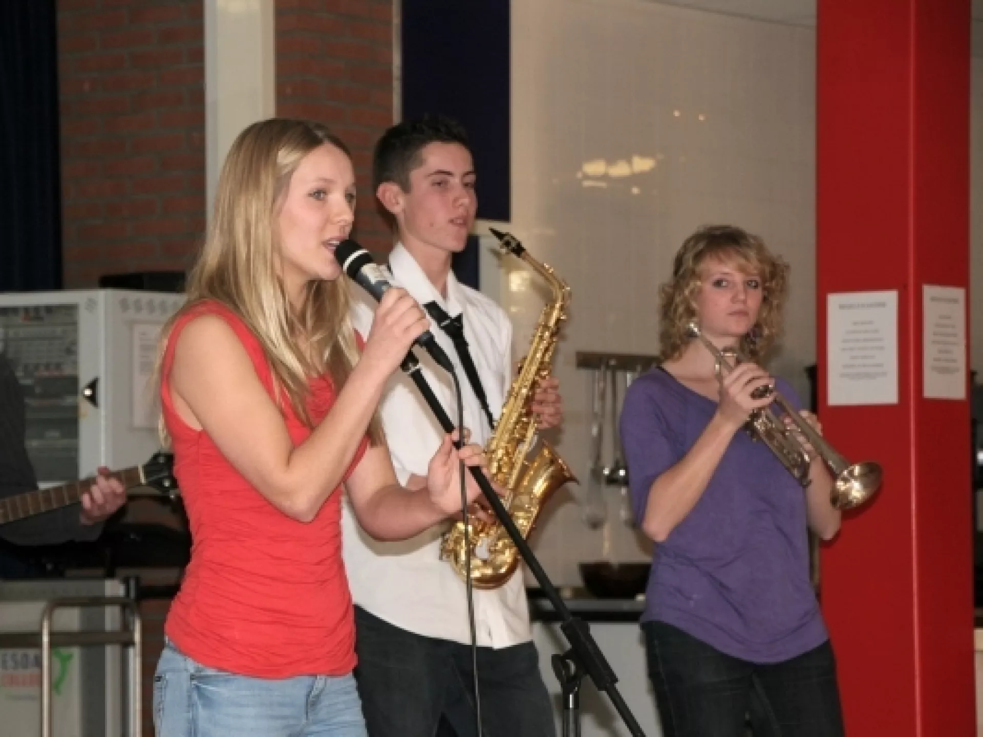 Drie jonge muzikanten met sax, trompet en microfoon
