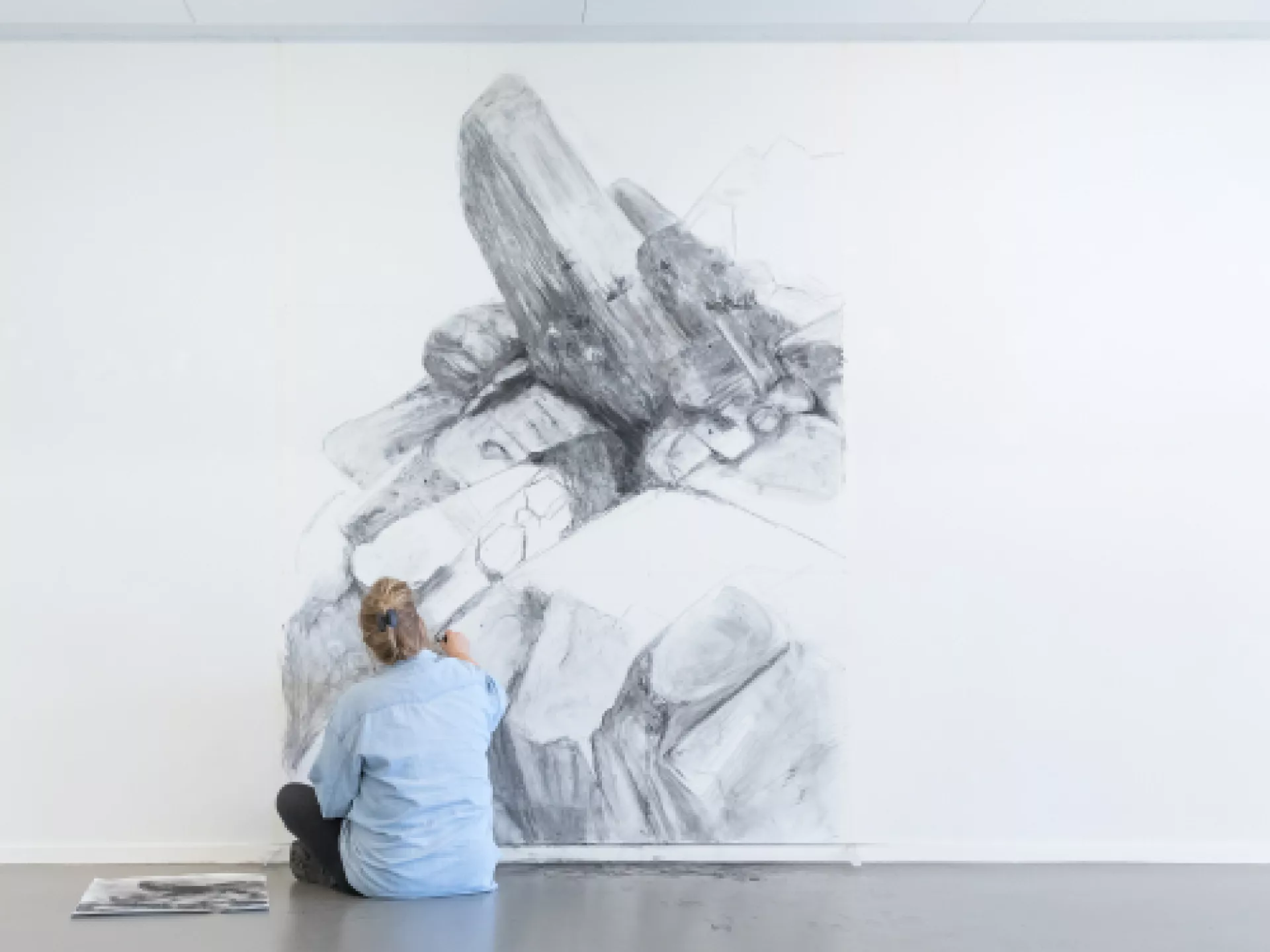 Een persoon tekent een grote zwart-wittekening op een muur.