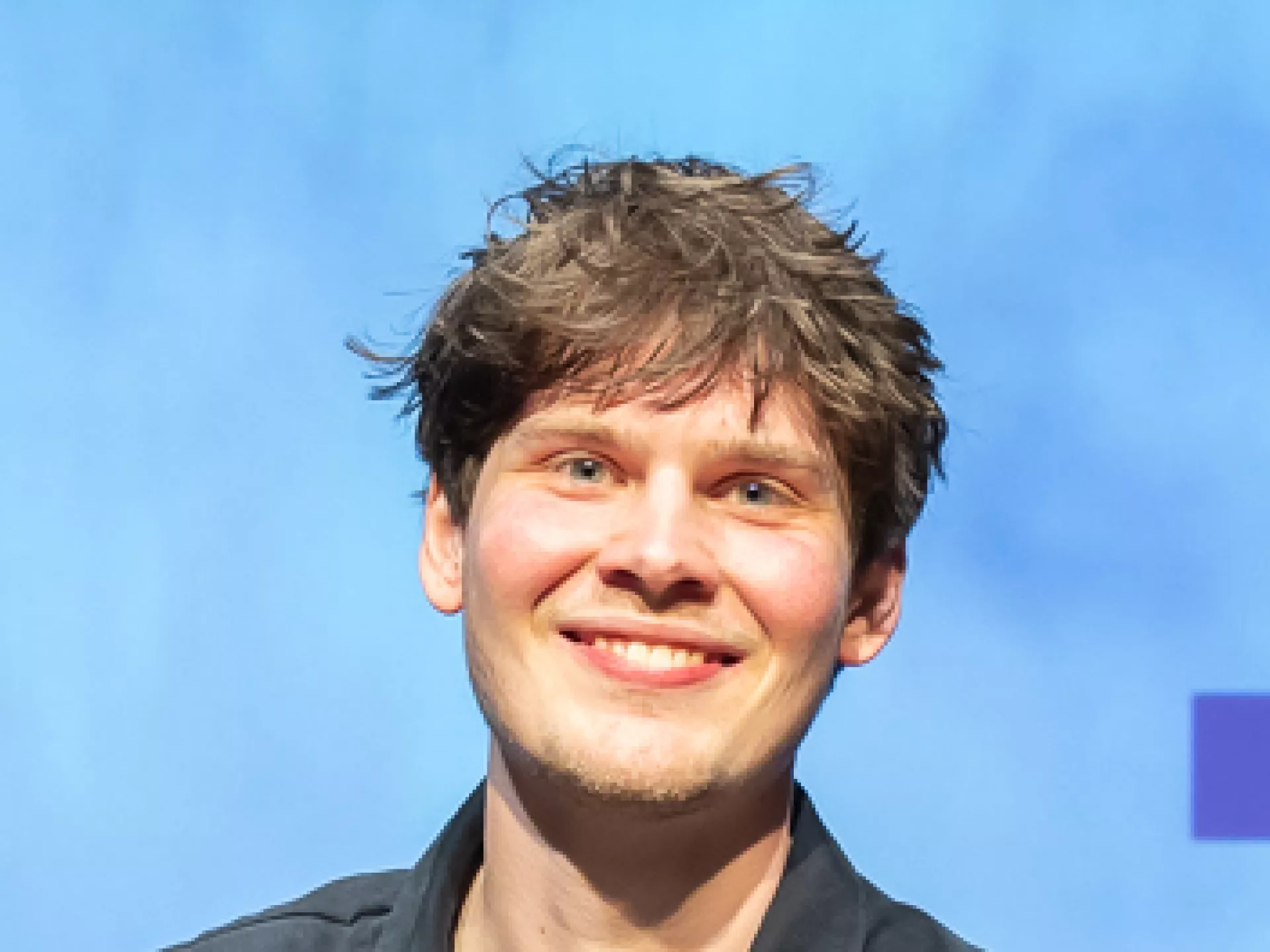 Winnaar Micha poseert met cheque van €2.500, sculptuur en bloemen op het podium.