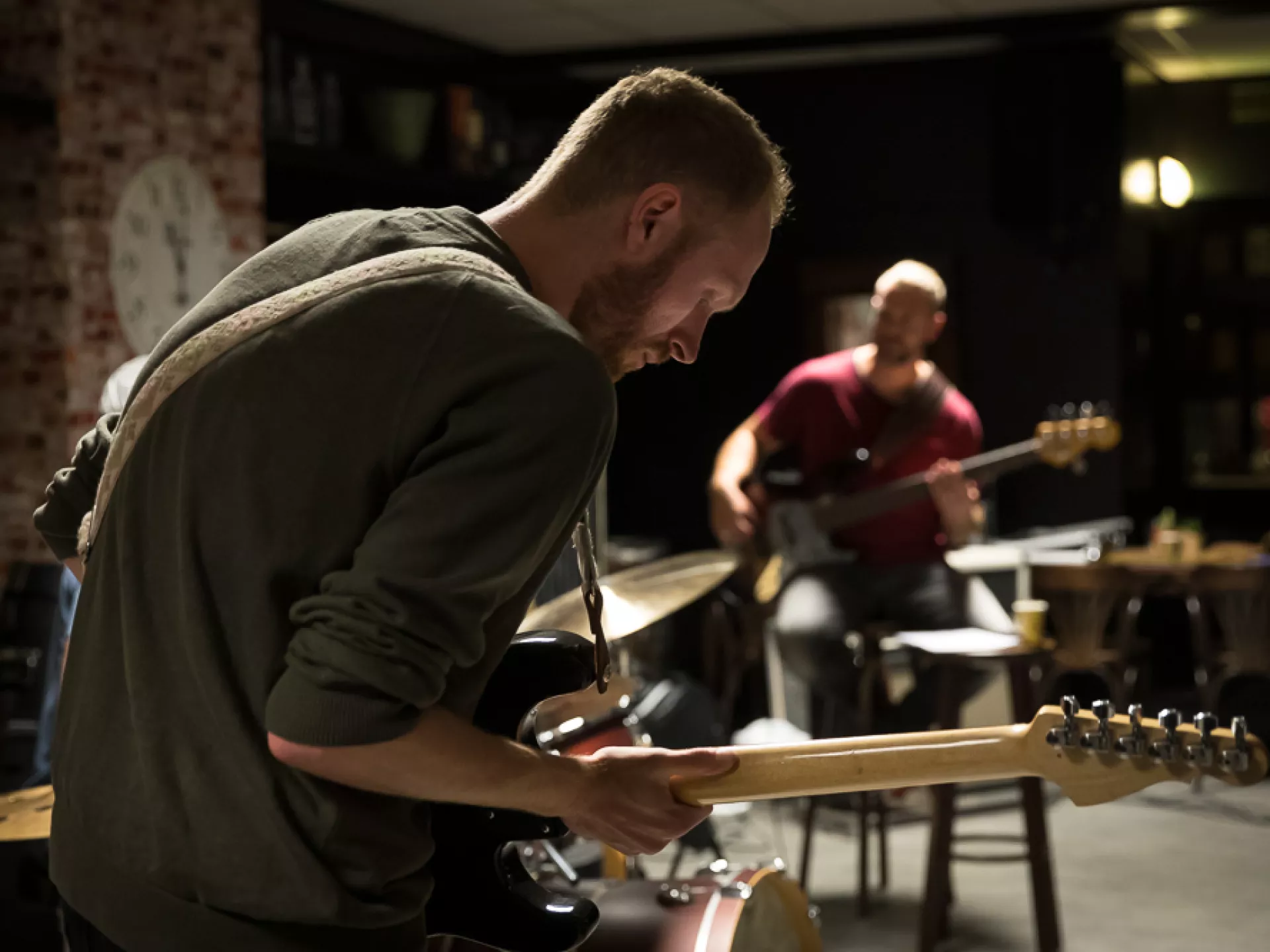 Twee muzikanten spelen elektrische gitaar in een sfeervolle ruimte.