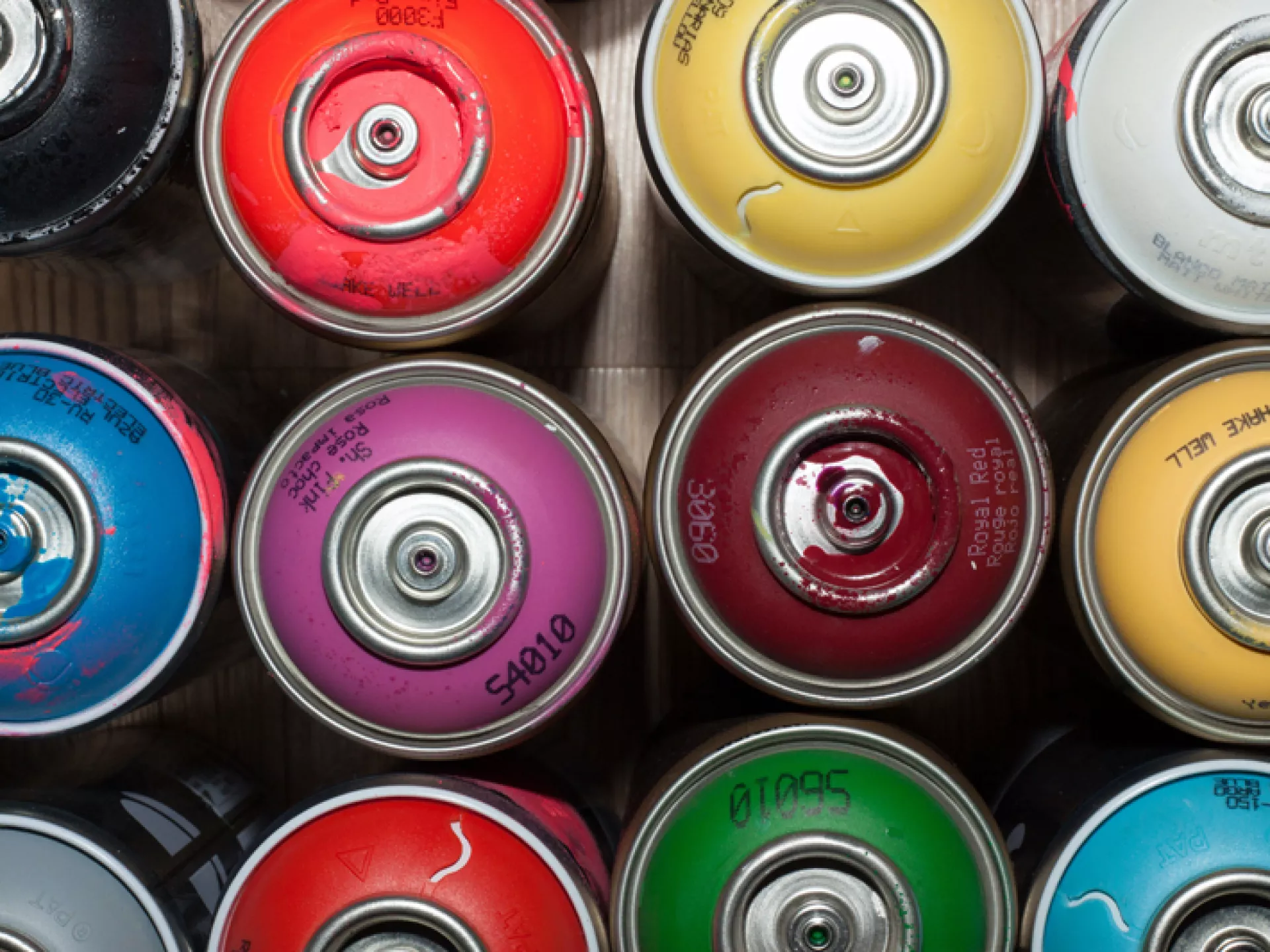 Blikjes spuitverf in verschillende kleuren van bovenaf bekeken.
