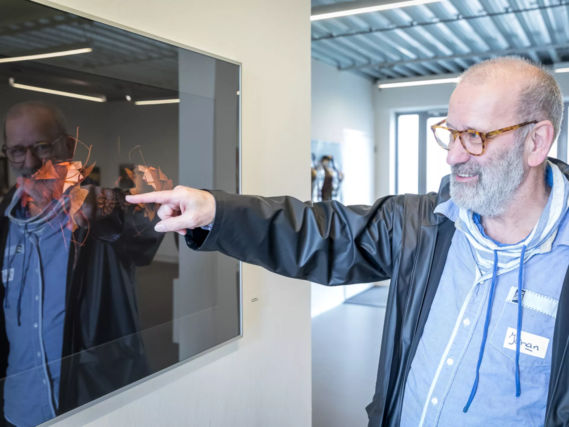 Een man wijst naar een kunstwerk in een galerie.