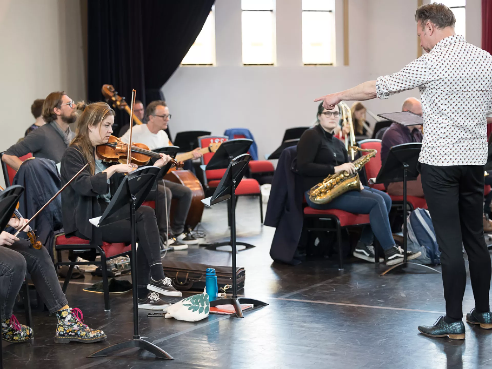 Muzikanten repeteren onder leiding van een dirigent.