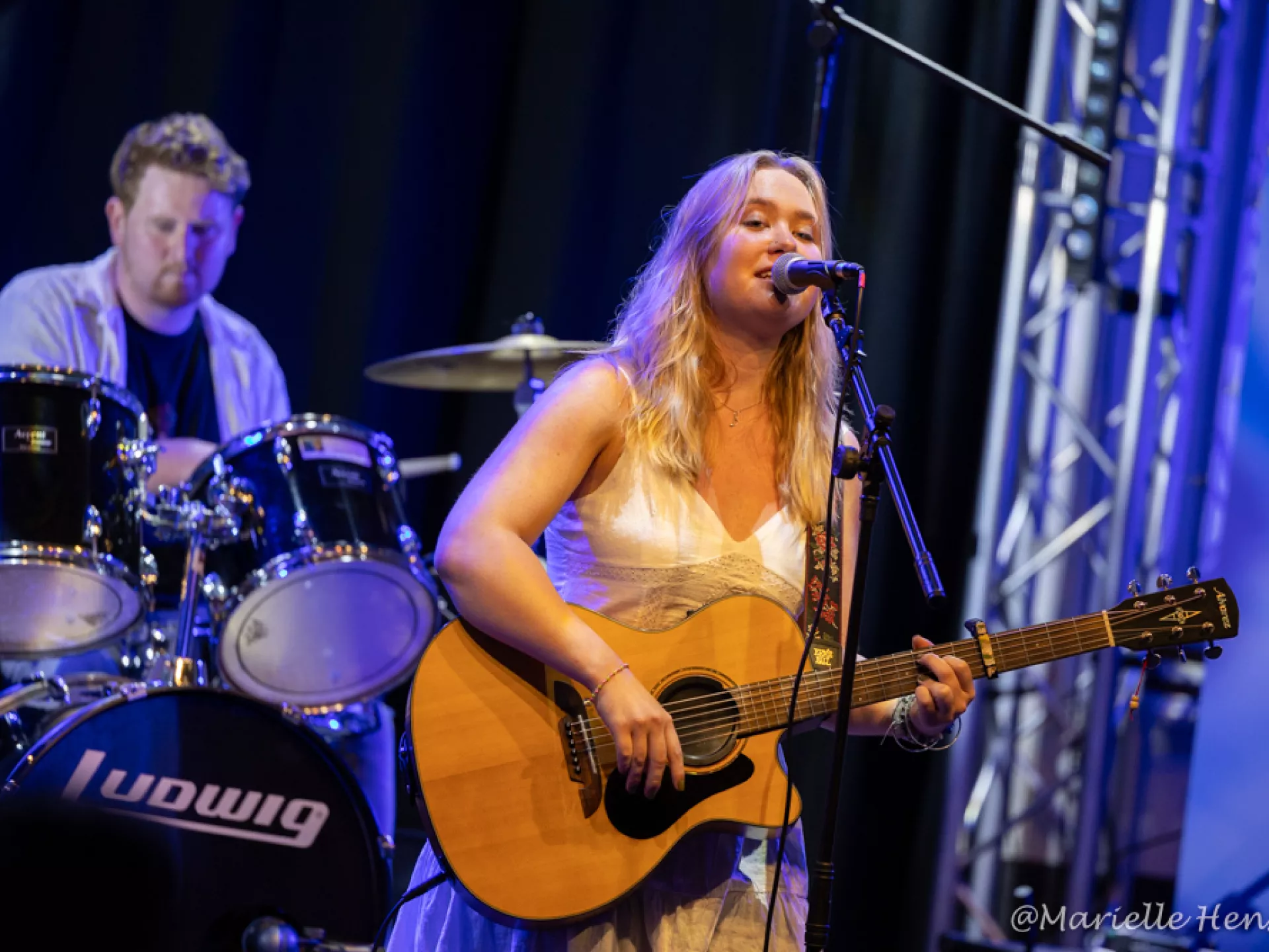 De zangeres van Bloom met op de achtergrond de drummer van de band.