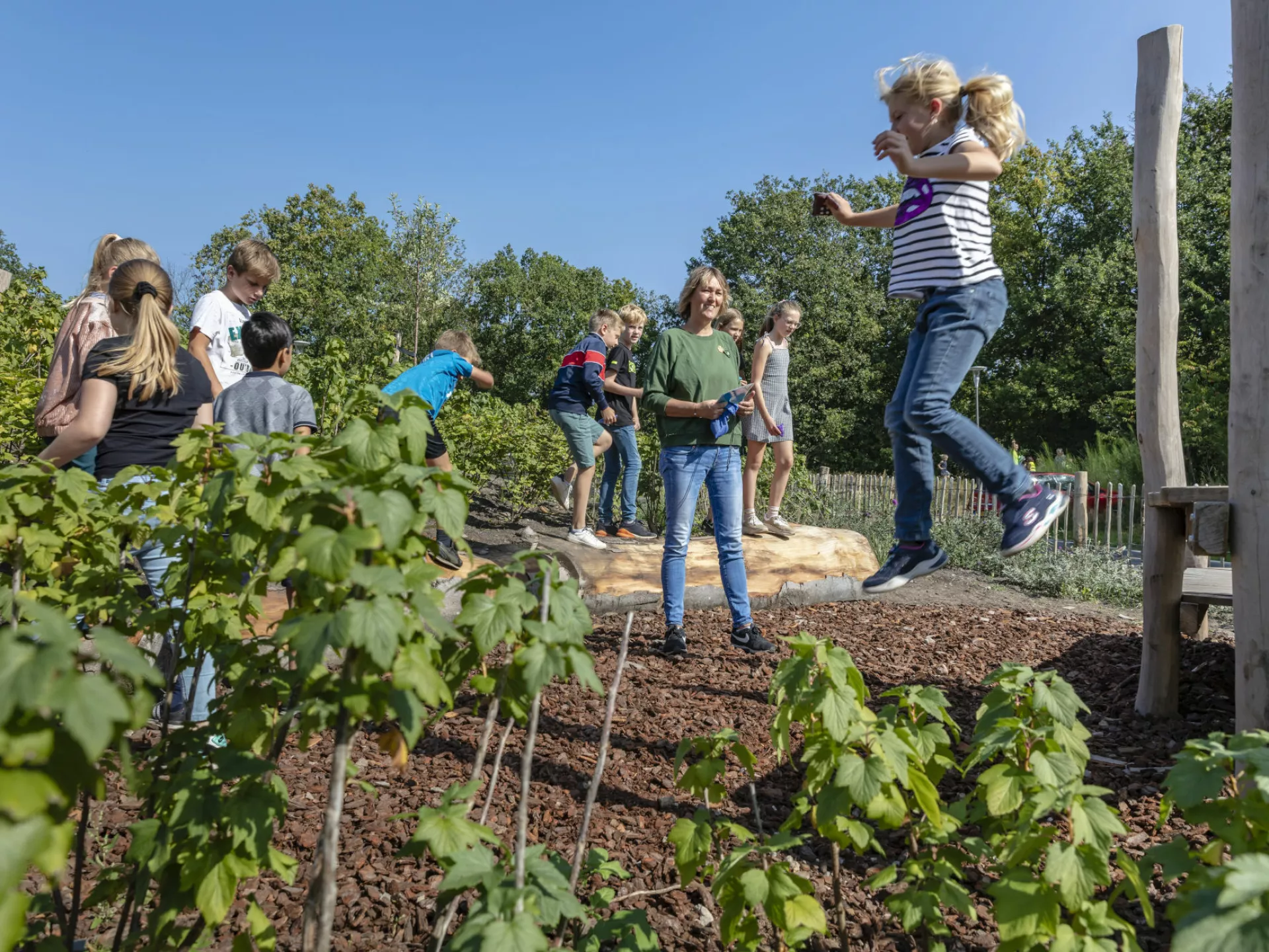 Het Buitenlokaal - Natuureducatie - Kind dat springt in een groene omgeving.