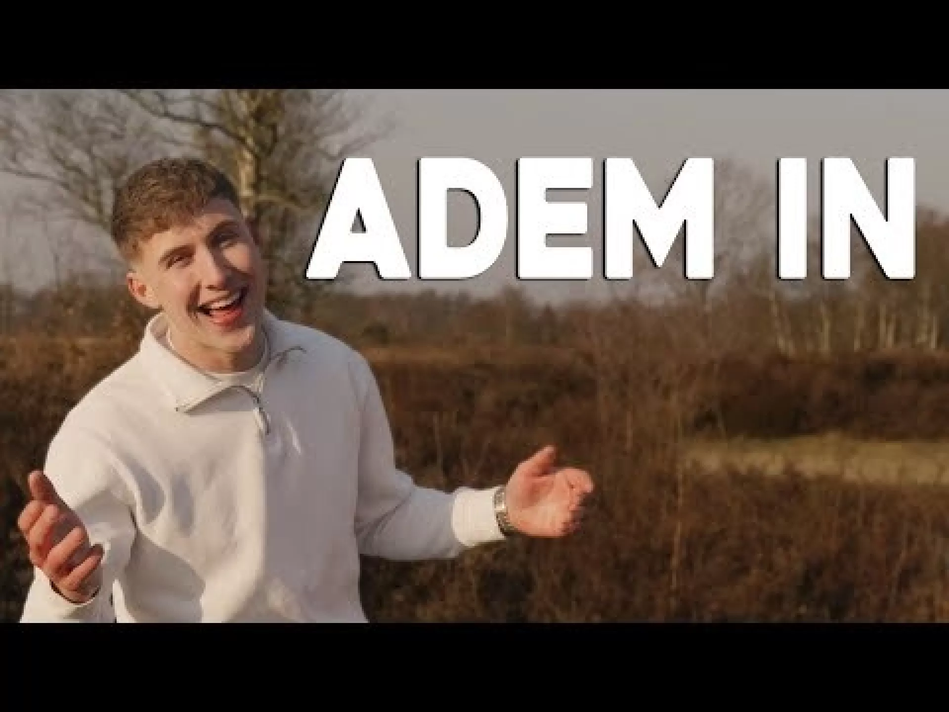 Ruben staat in een witte trui in een natuurgebied met de titel van zijn single 'Adem in'.