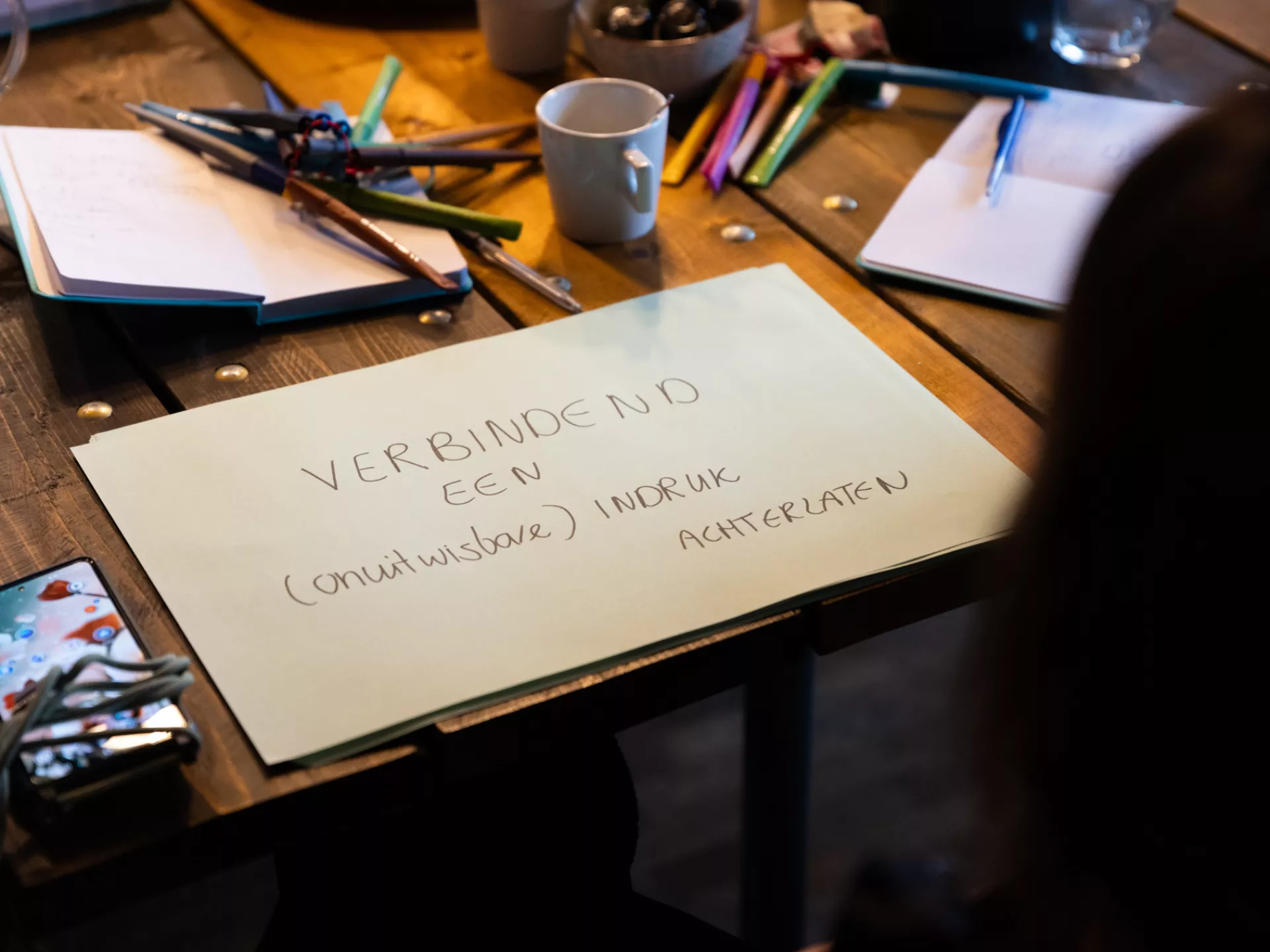 Rond een tafel liggen schrijfmaterialen en een vel papier met notities.