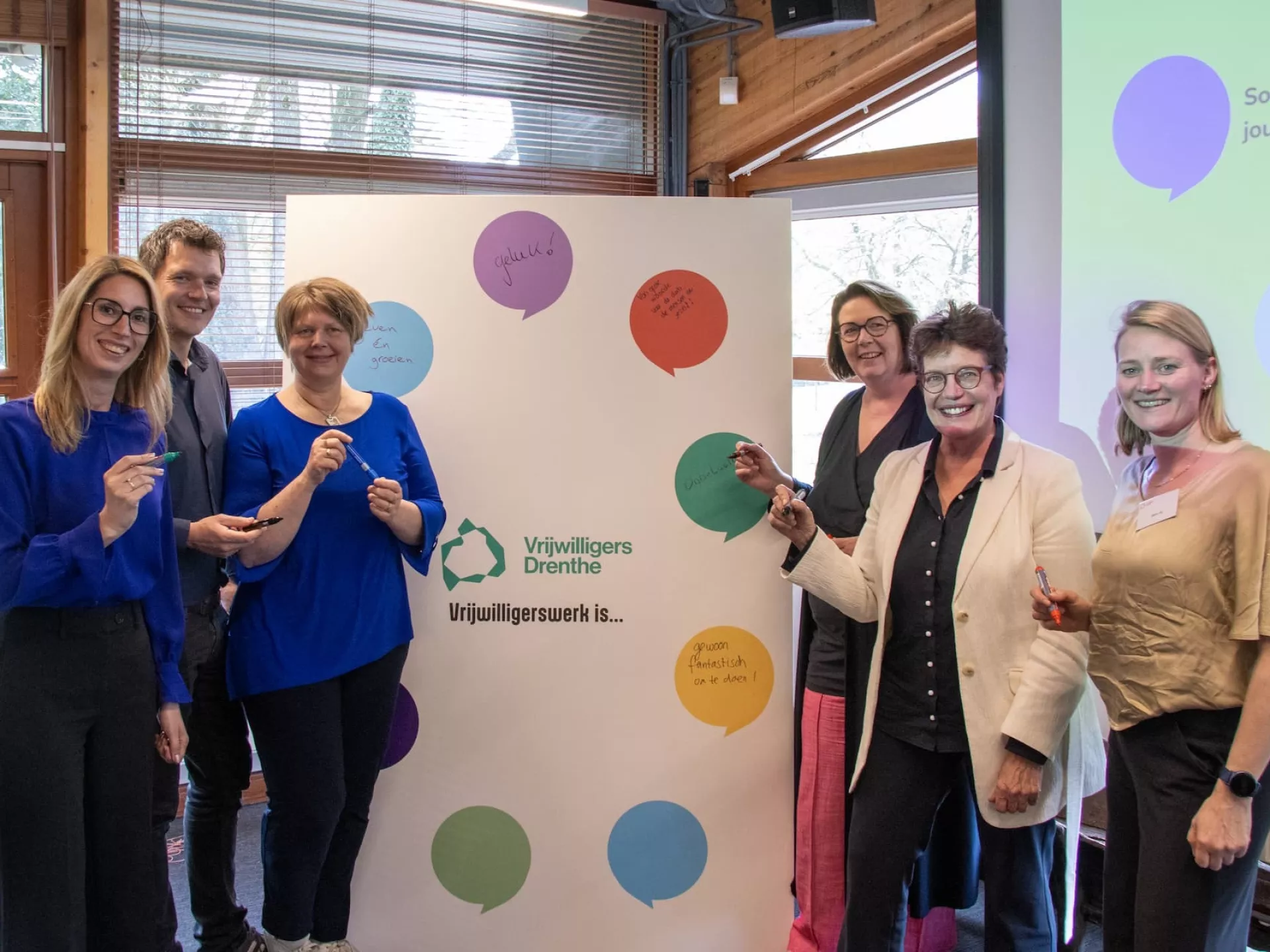Groep mensen poseert voor een bord met kleurrijke stippen.