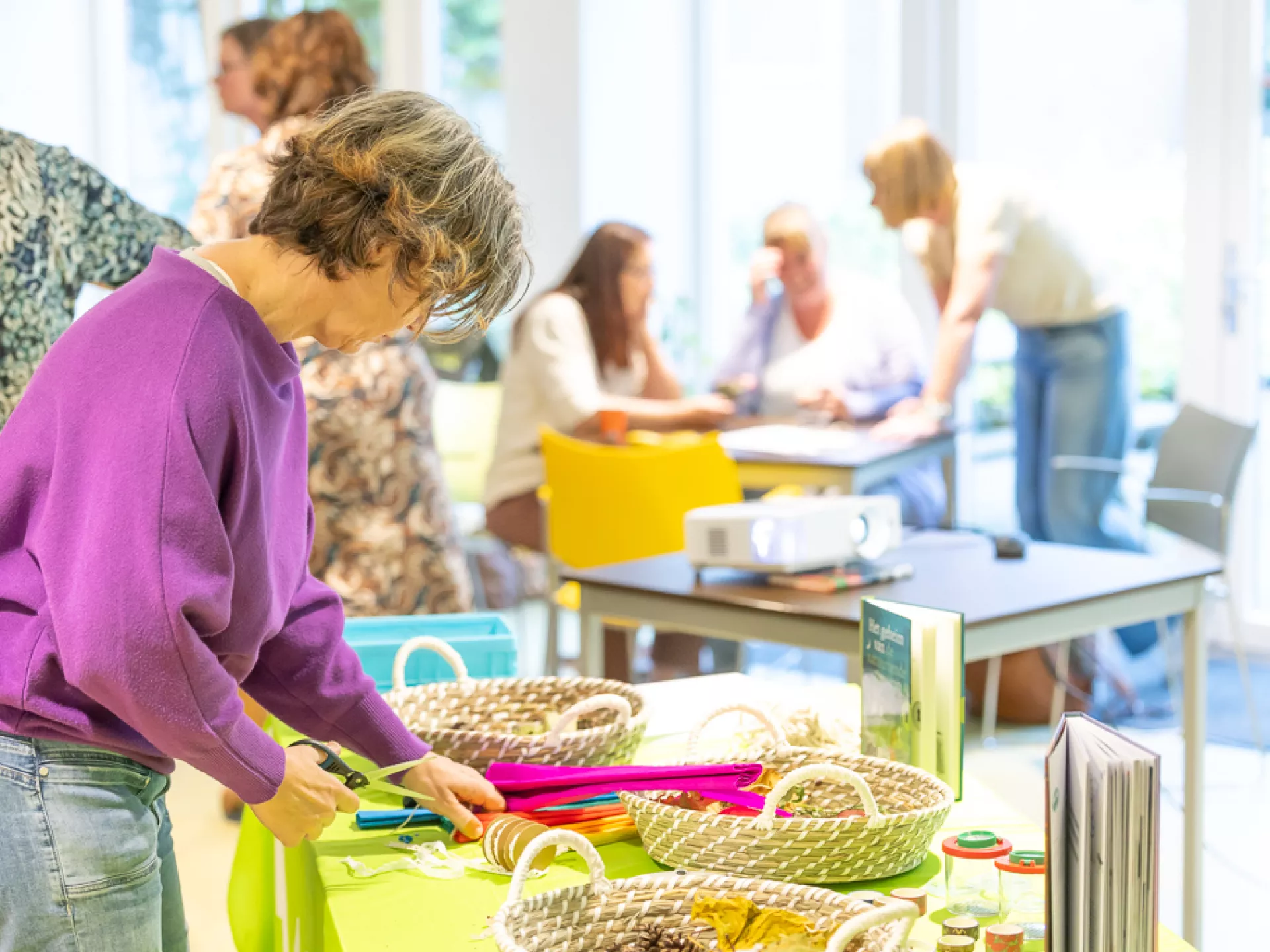 Een vrouw werkt aan een creatief project aan een tafel vol materialen.