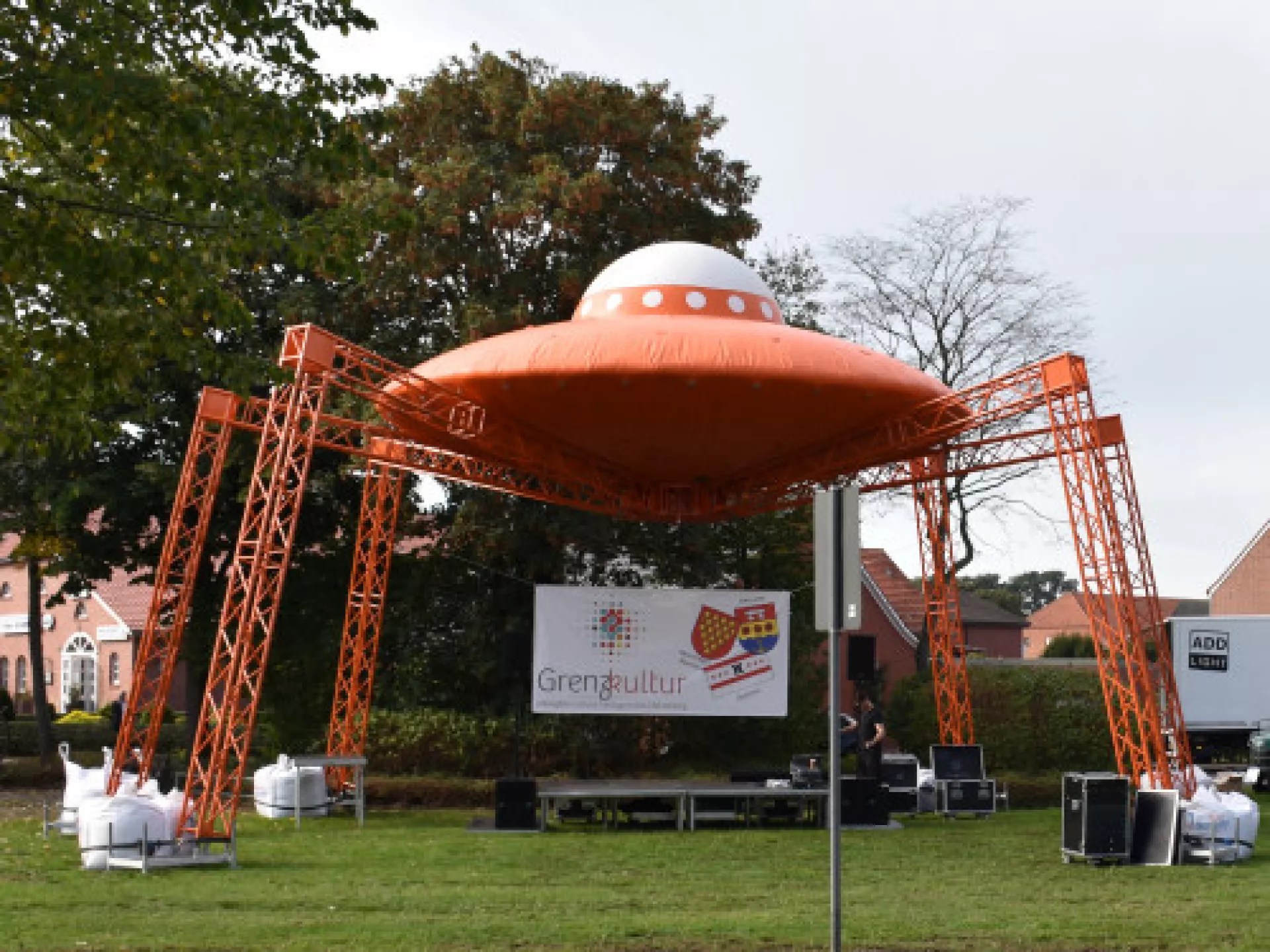 Opblaasbare UFO-structuur met metalen poten op een grasveld.
