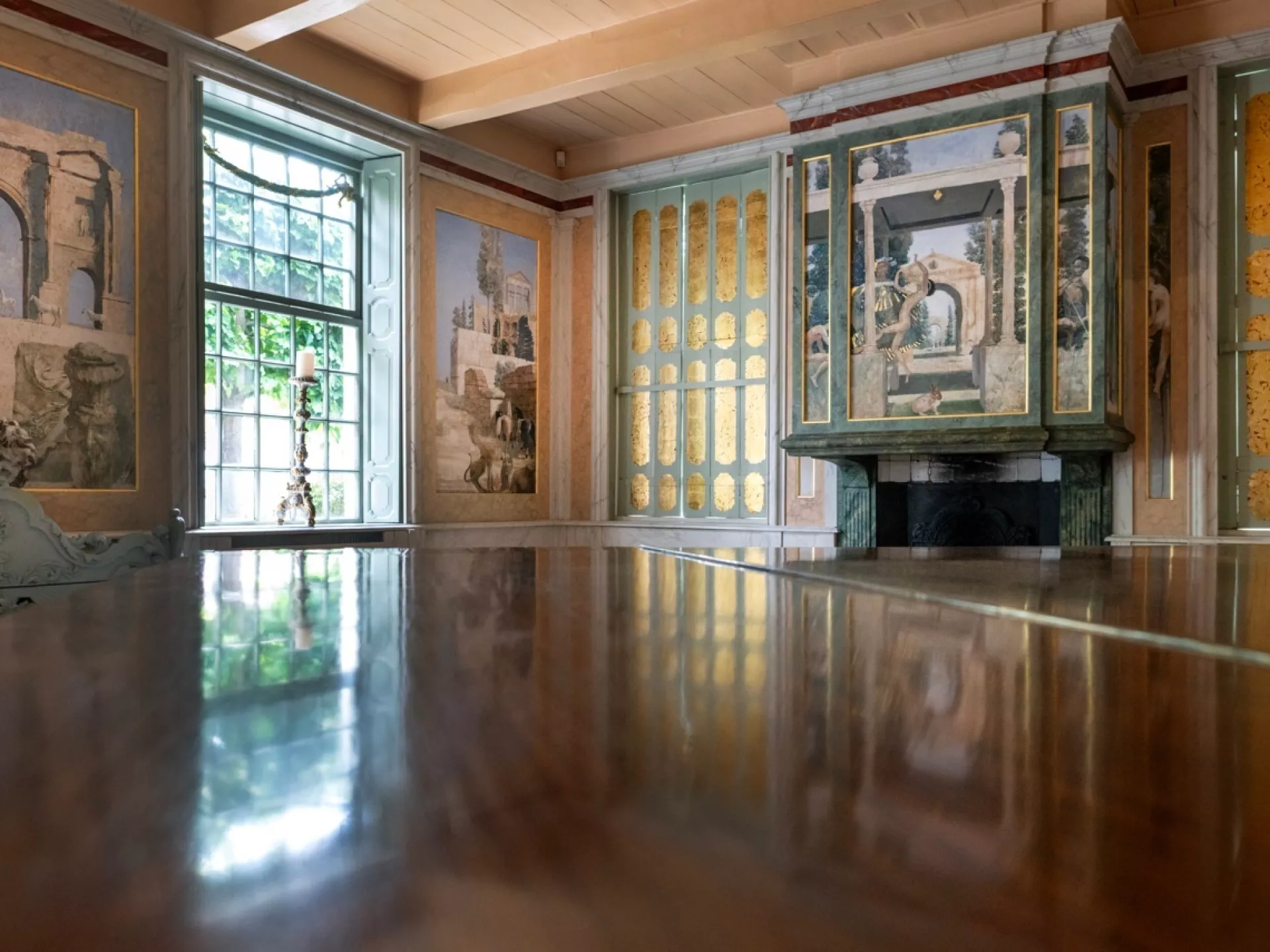 Historische kamer met gedecoreerde muren en een groot raam.