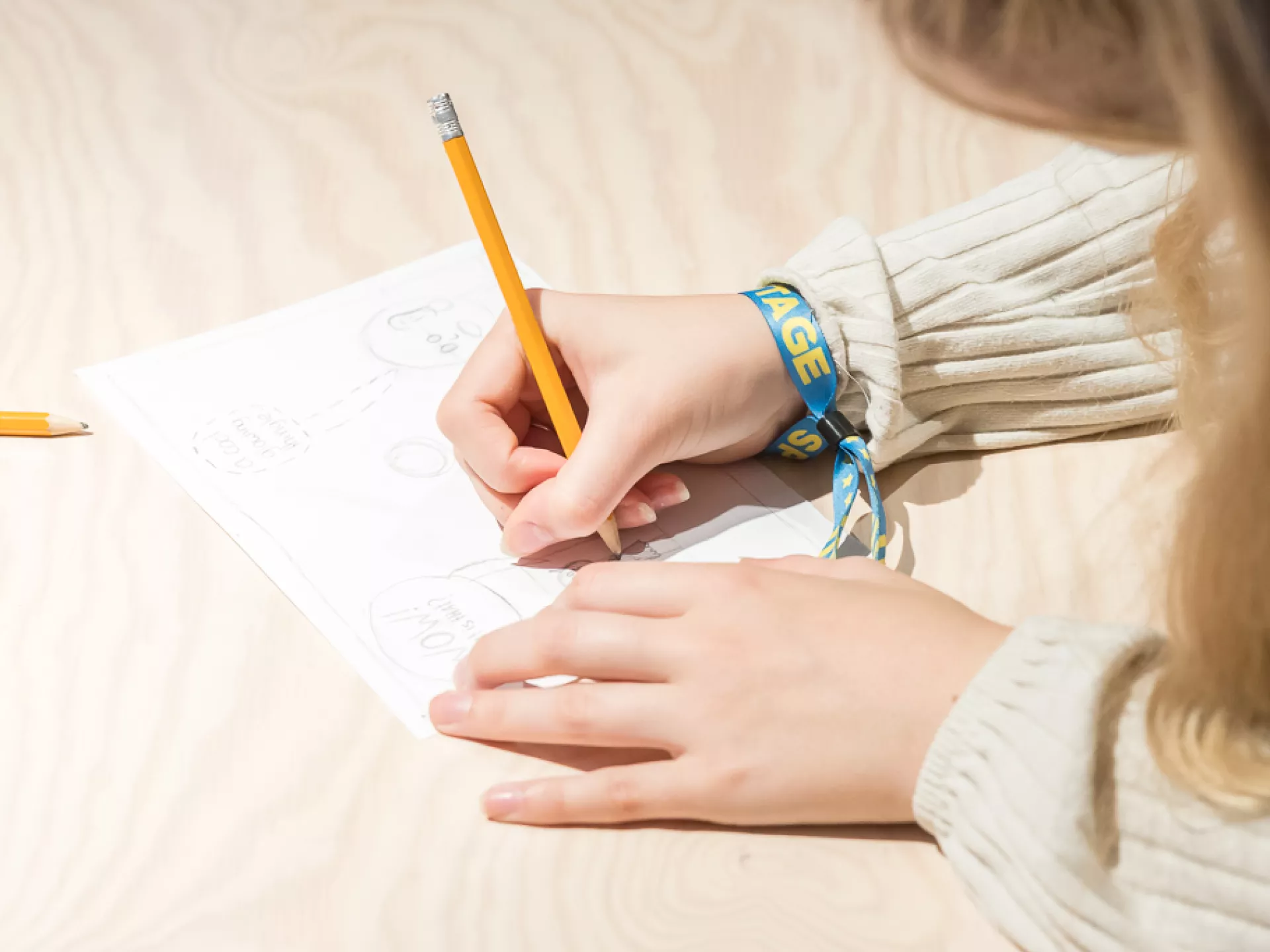 Een persoon schrijft met een potlood op papier.