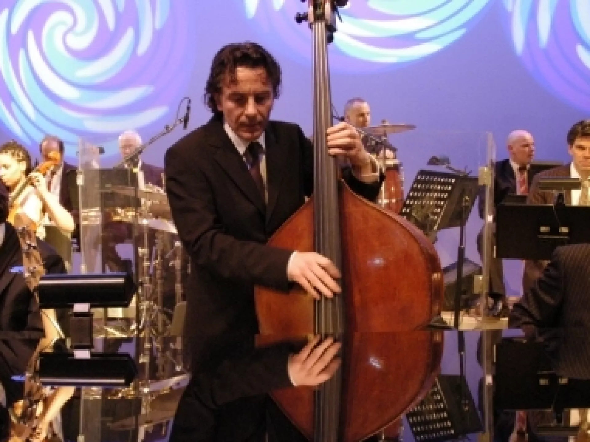 Muzikant met contrabas met op achtergrond orkest