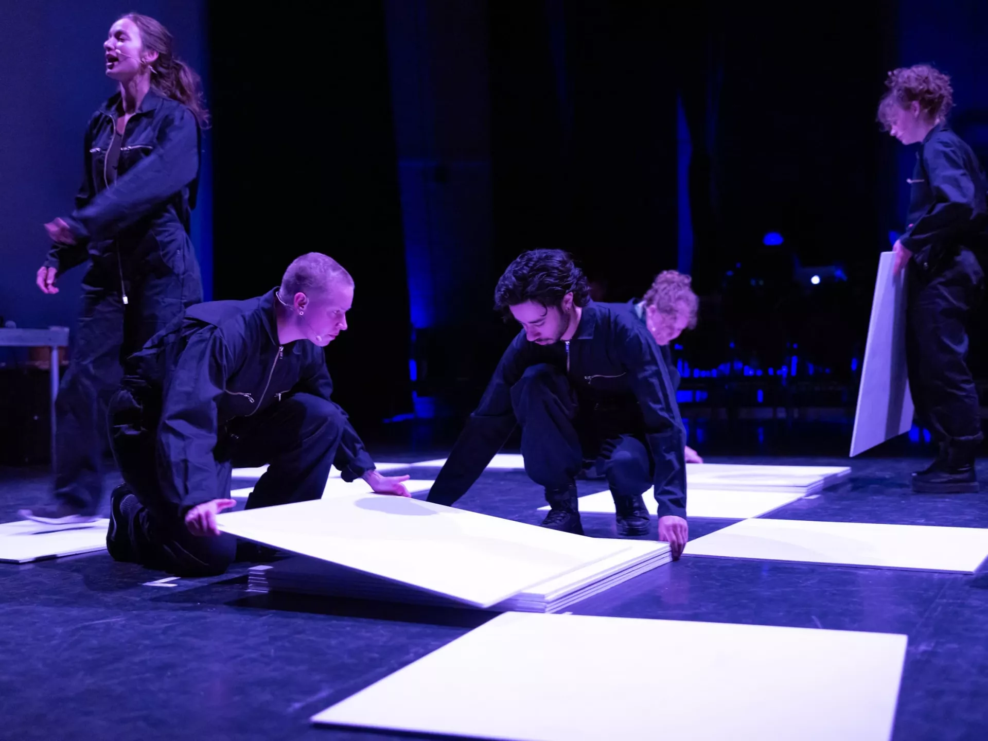 Een groep mensen in zwarte kleding werkt samen op een podium.