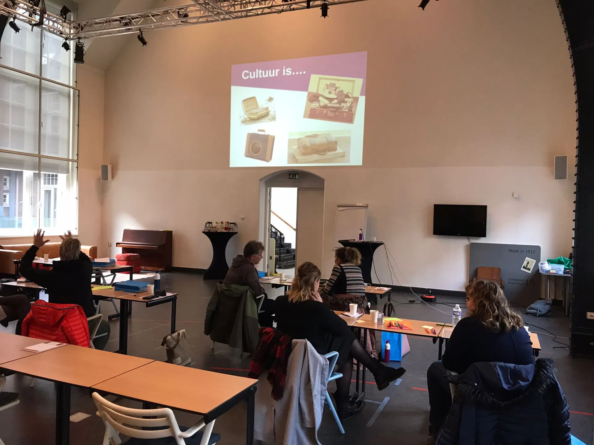 Groep mensen in een klaslokaal met een presentatie over cultuur.