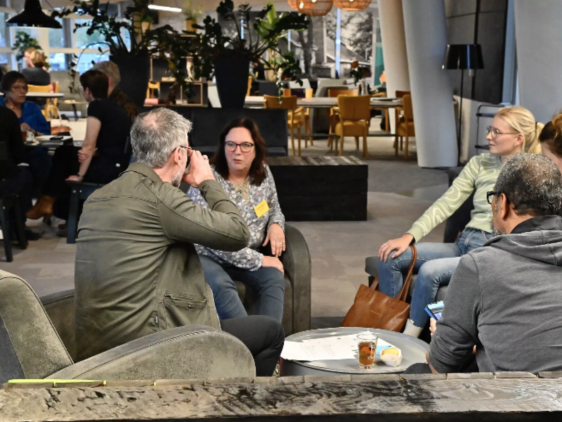 Groep mensen in gesprek in een moderne, gezellige ruimte.