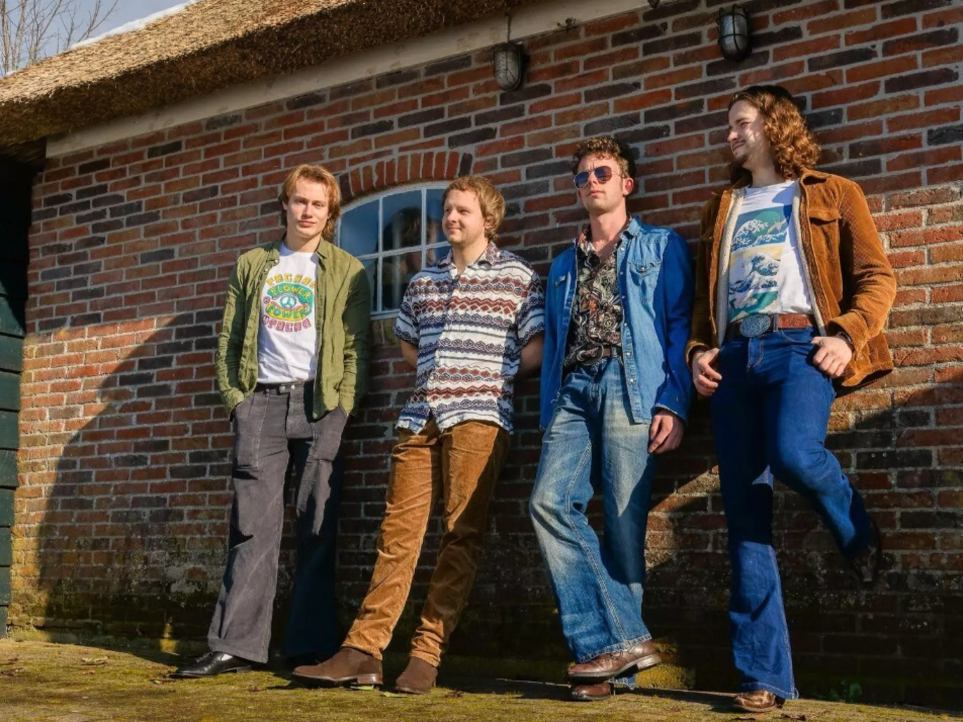 Vier bandleden poseren voor een boederij