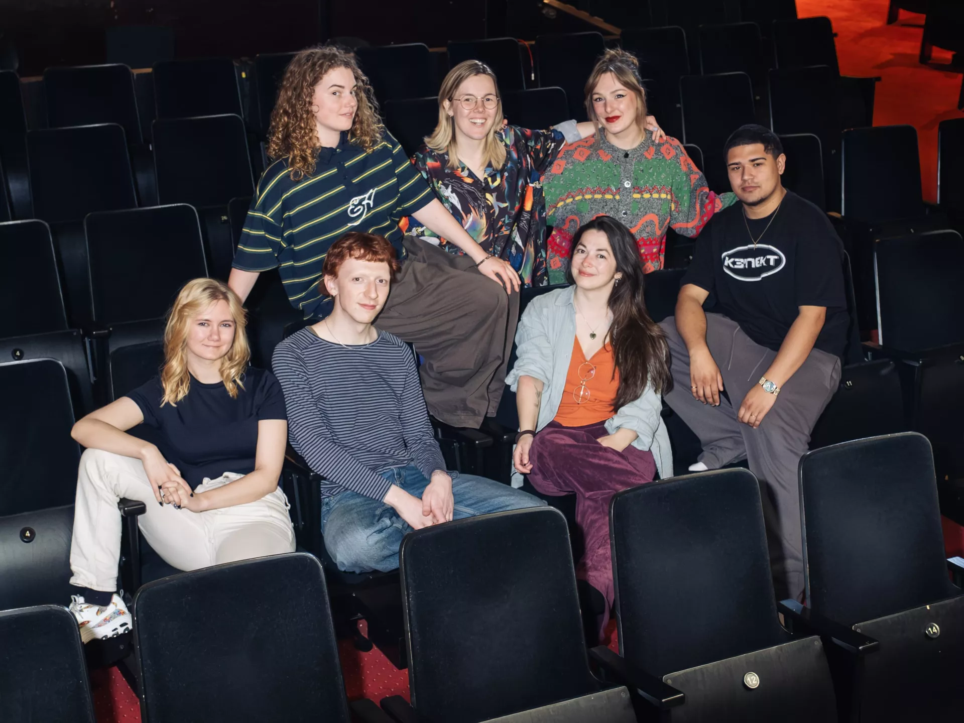 Groep mensen poseert samen in een theaterzaal.