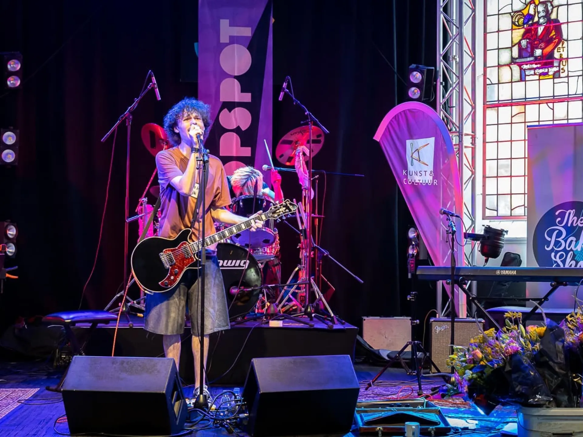 Een band treedt op op een kleurrijk verlicht podium.