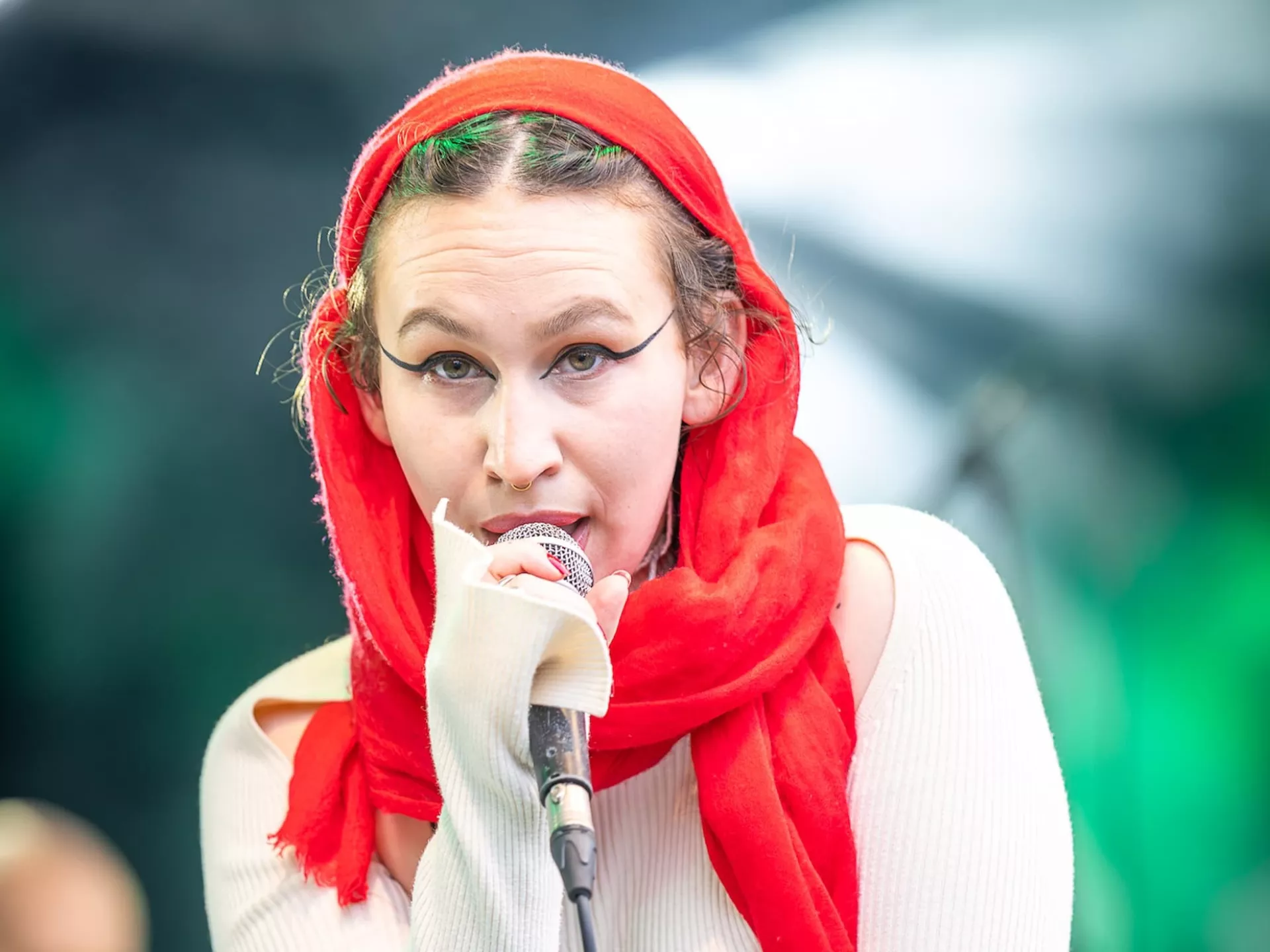 Vrouw zingt met rode sjaal op podium.