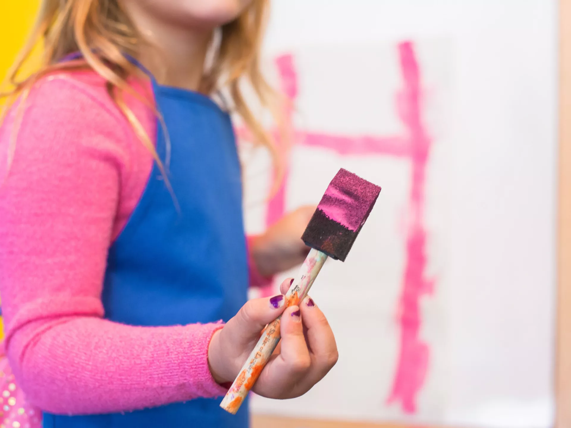 Een kind schildert met een penseel op papier.