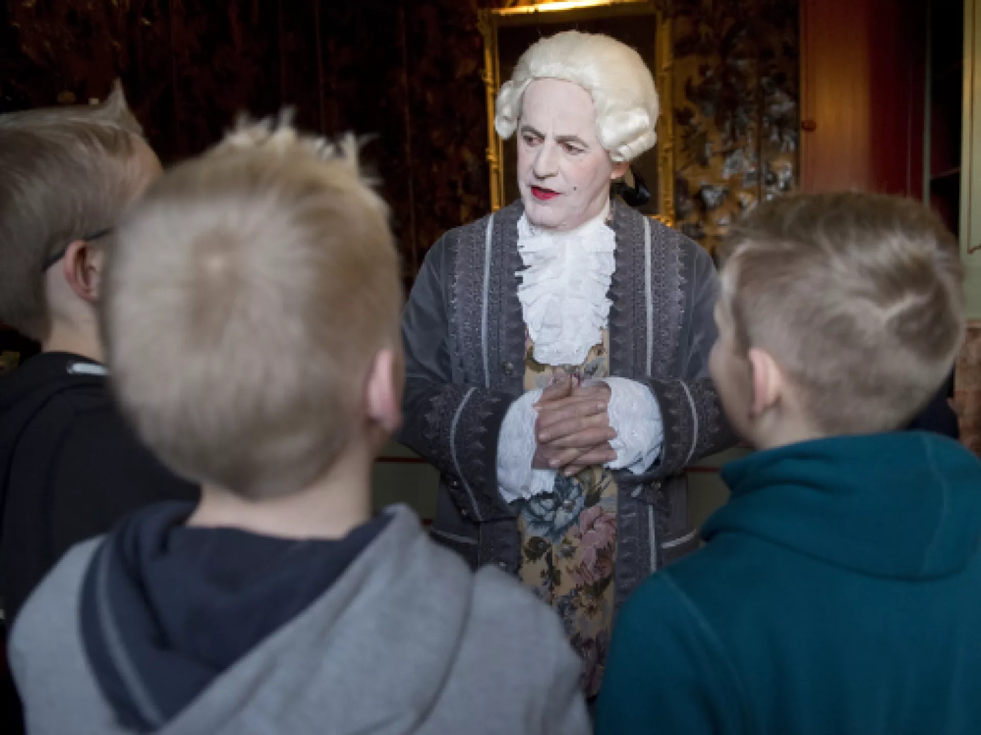 Persoon in historische kleding praat met kinderen.