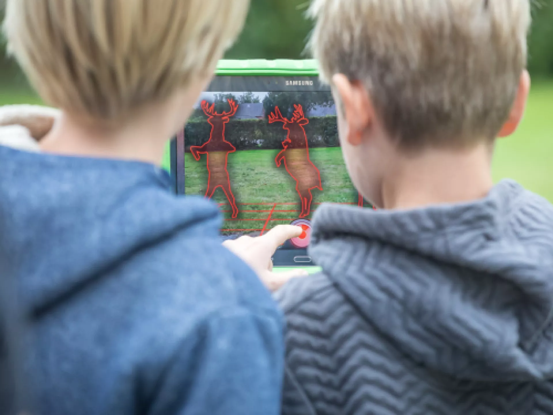Twee kinderen spelen een digitaal spel op een tablet.