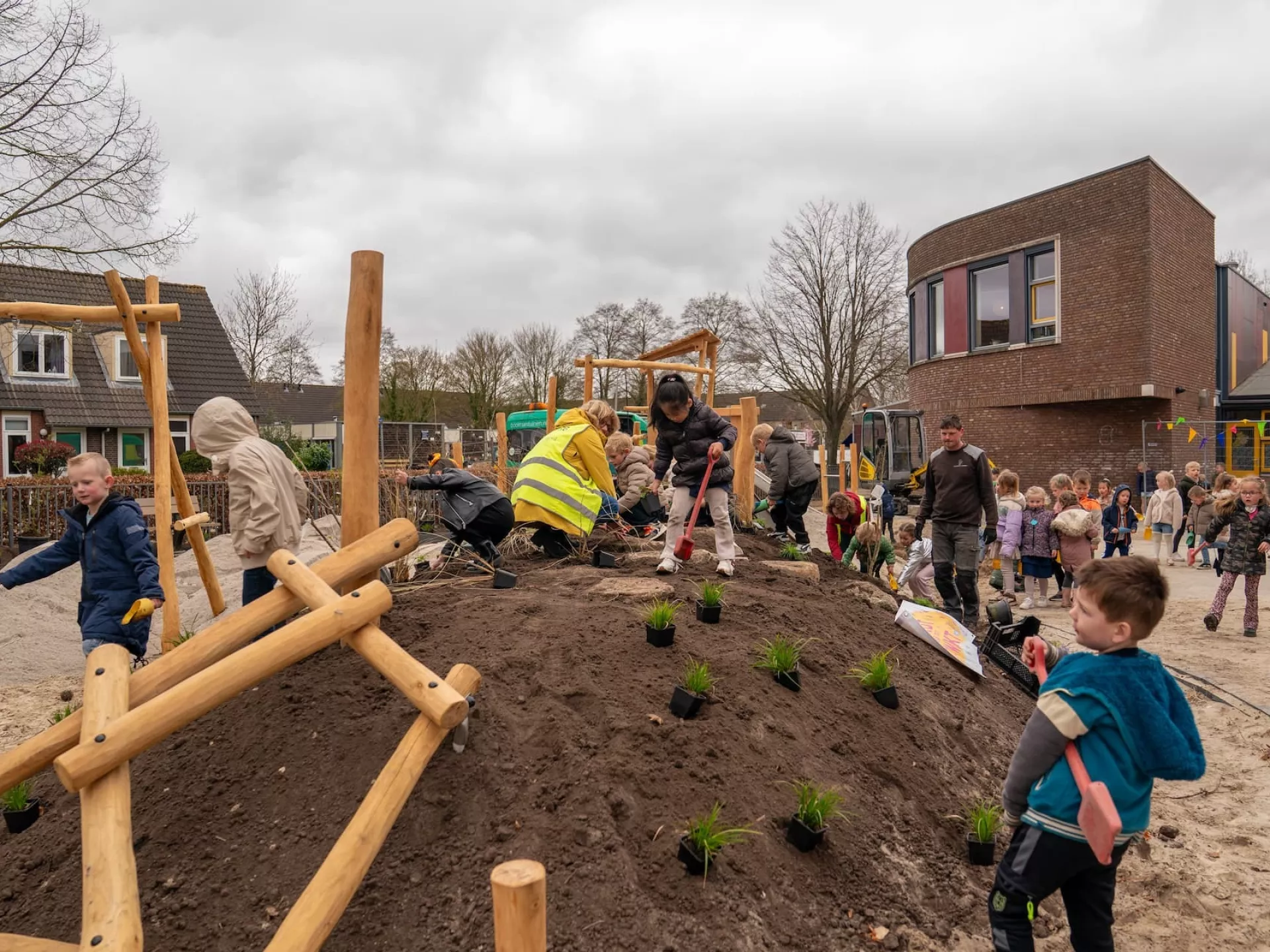 Kinderen en volwassenen werken samen aan de vernieuwing van het schoolplein.