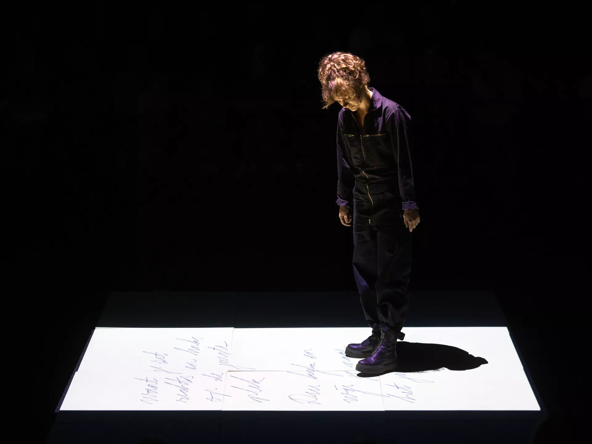 Een persoon staat op een podium in een donkere omgeving.