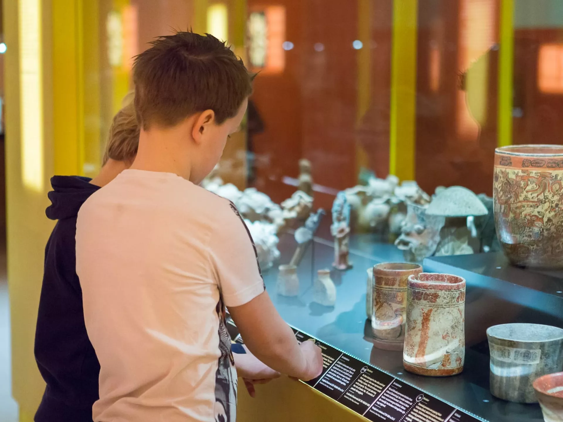 Twee jongens kijken in een vitrinekast tijdens een bezoek aan het museum.