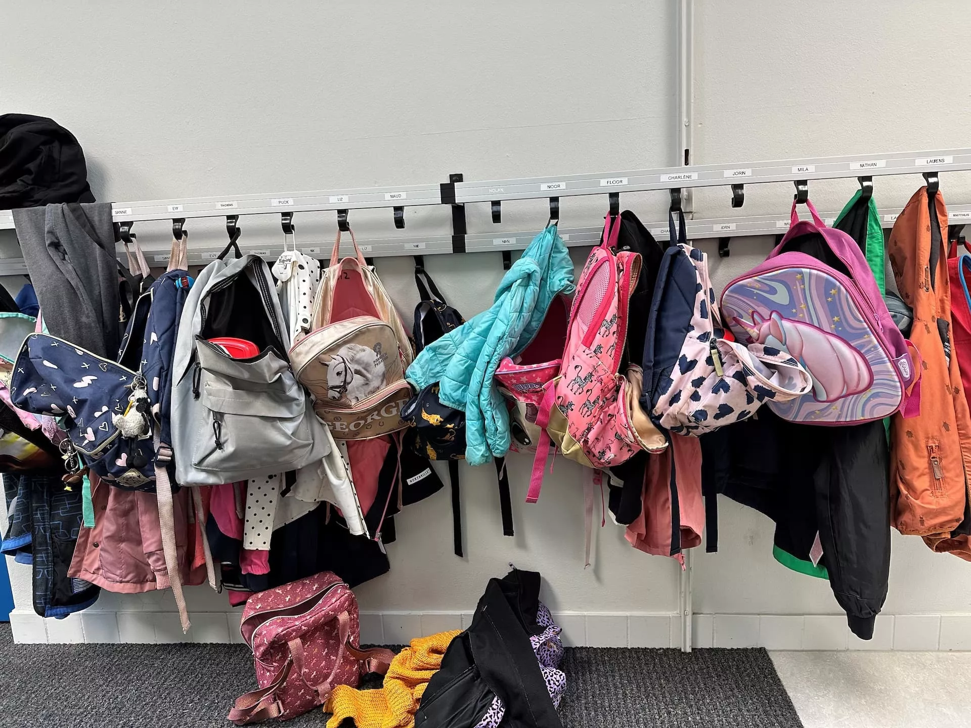Kinderjasjes en tasjes aan een kapstok.