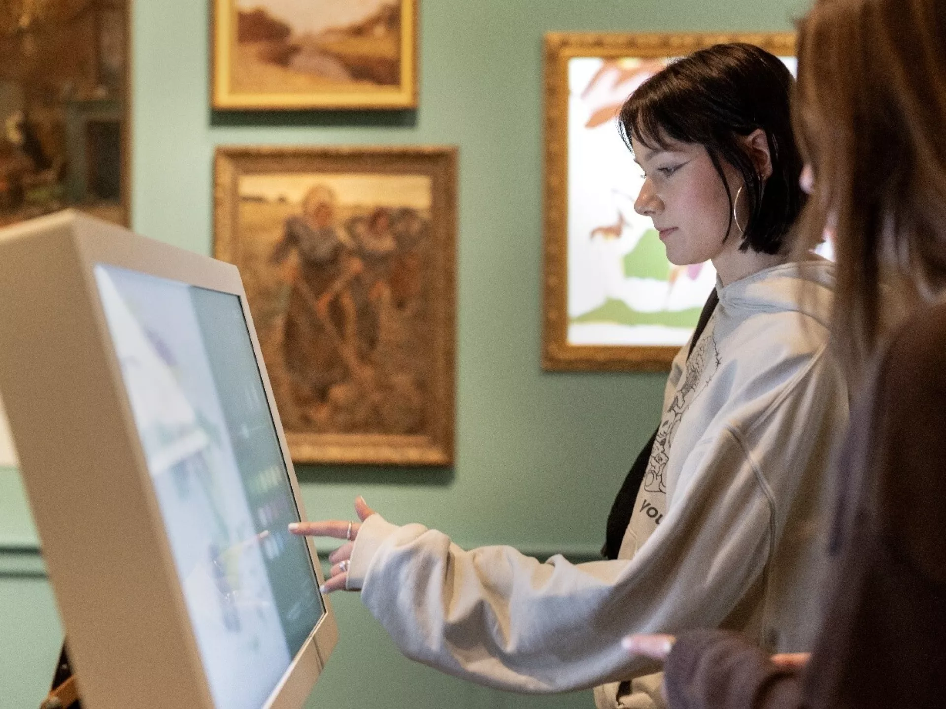 Twee mensen gebruiken interactieve schermen in een kunstmuseum.