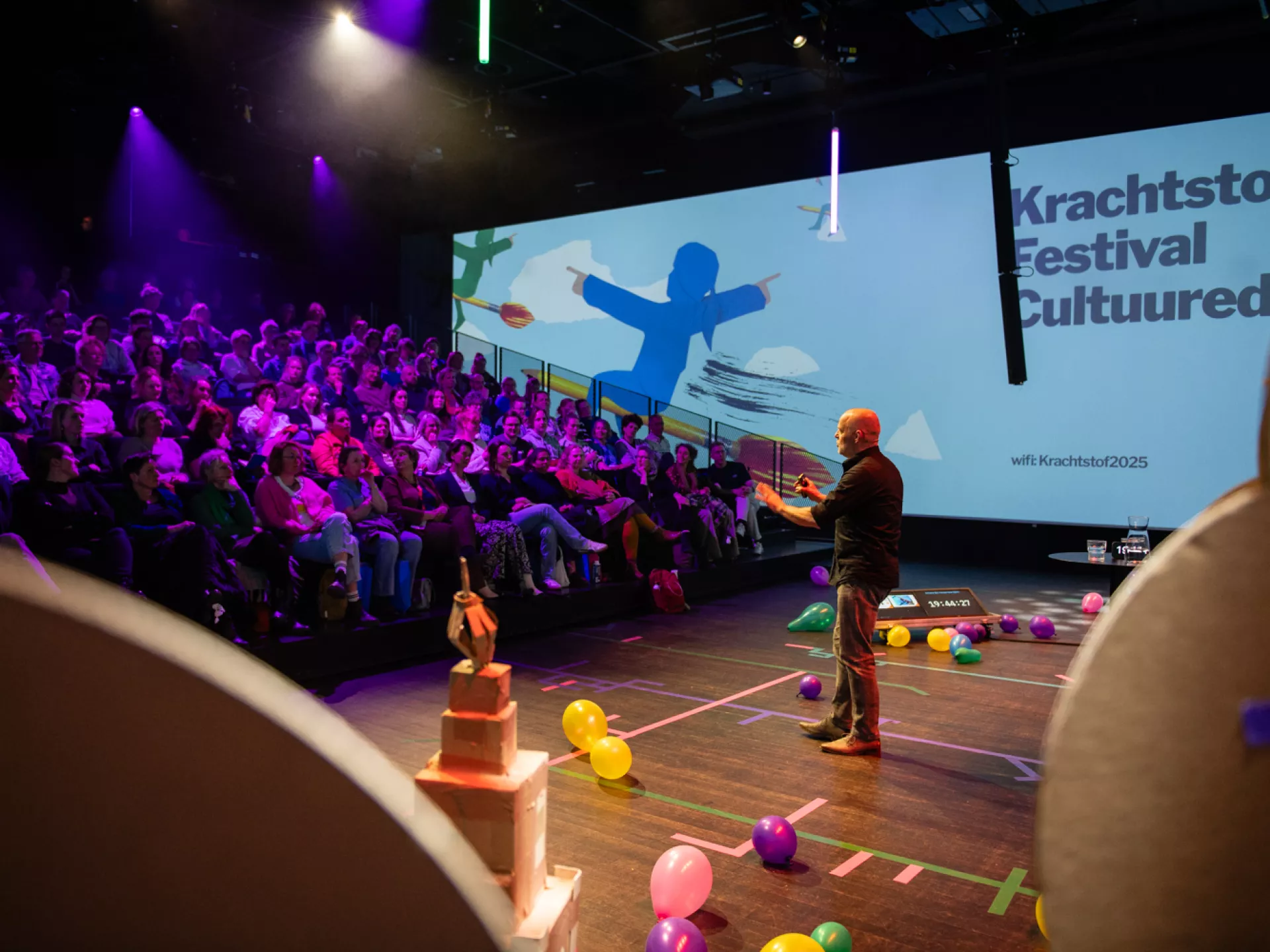 Een spreker op het podium tijdens het Krachtstof Festival met een aandachtig publiek.