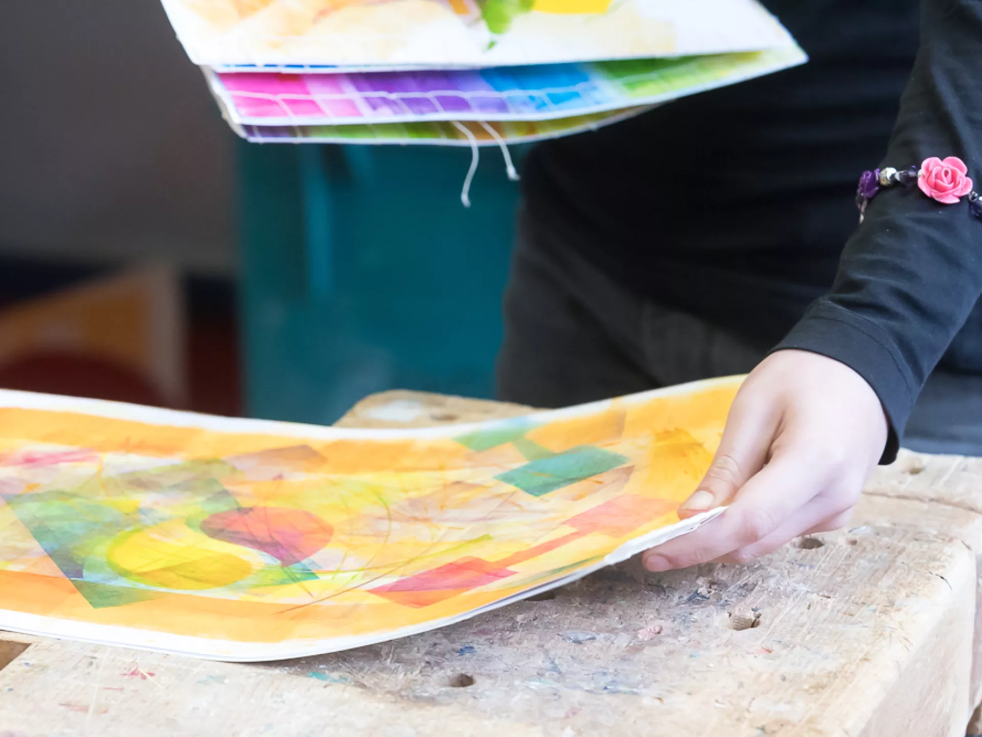 Een persoon houdt kleurrijke kunstwerken vast in een studio.