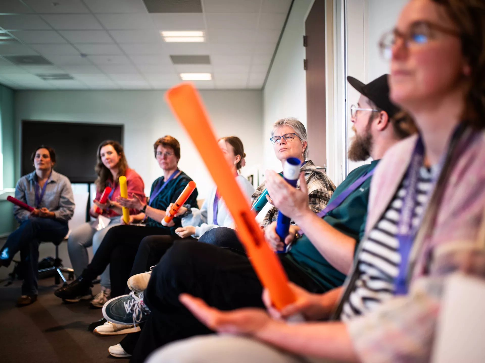 Mensen in een kring met percussie-instrumenten tijdens een groepsactiviteit.