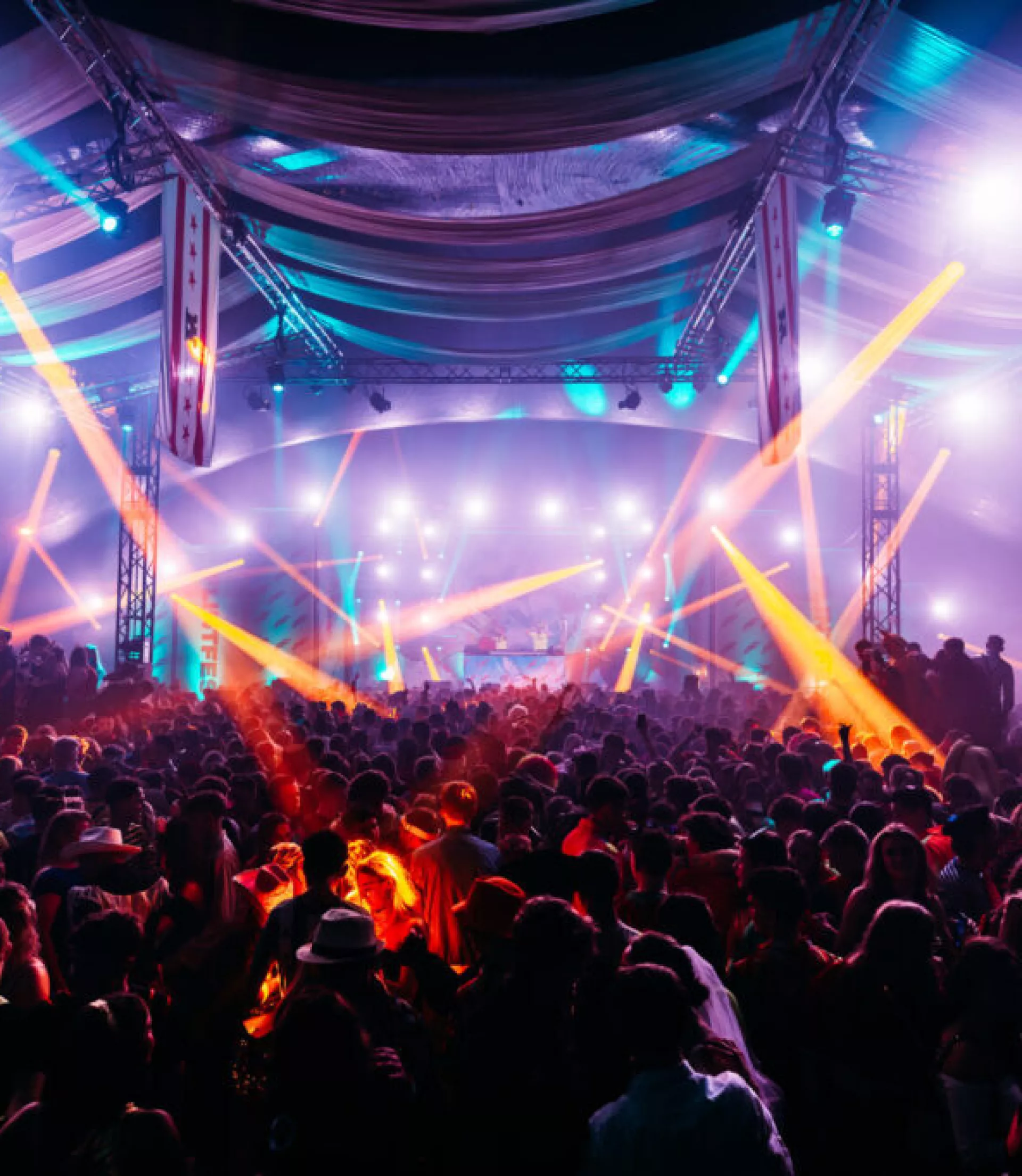 Een drukke concertzaal met kleurrijke verlichting en een enthousiast publiek.