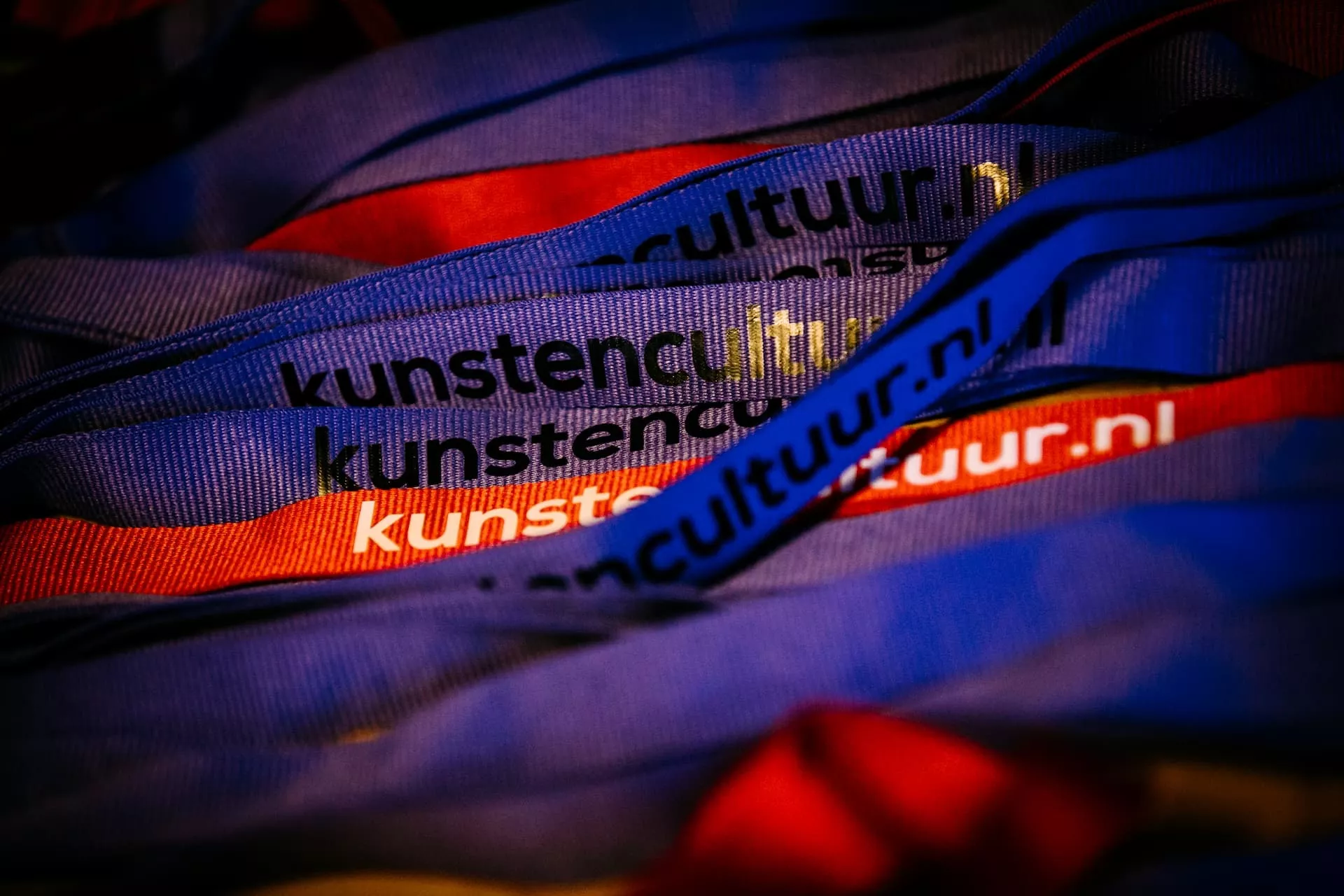 Stapel gekleurde polsbandjes met tekst "kunstencultuur.nl".