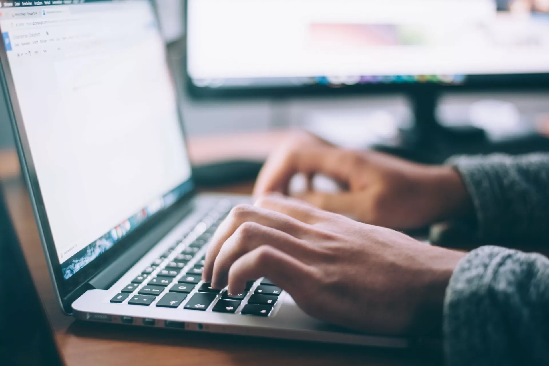 Laptop met twee handen van persoon die typt