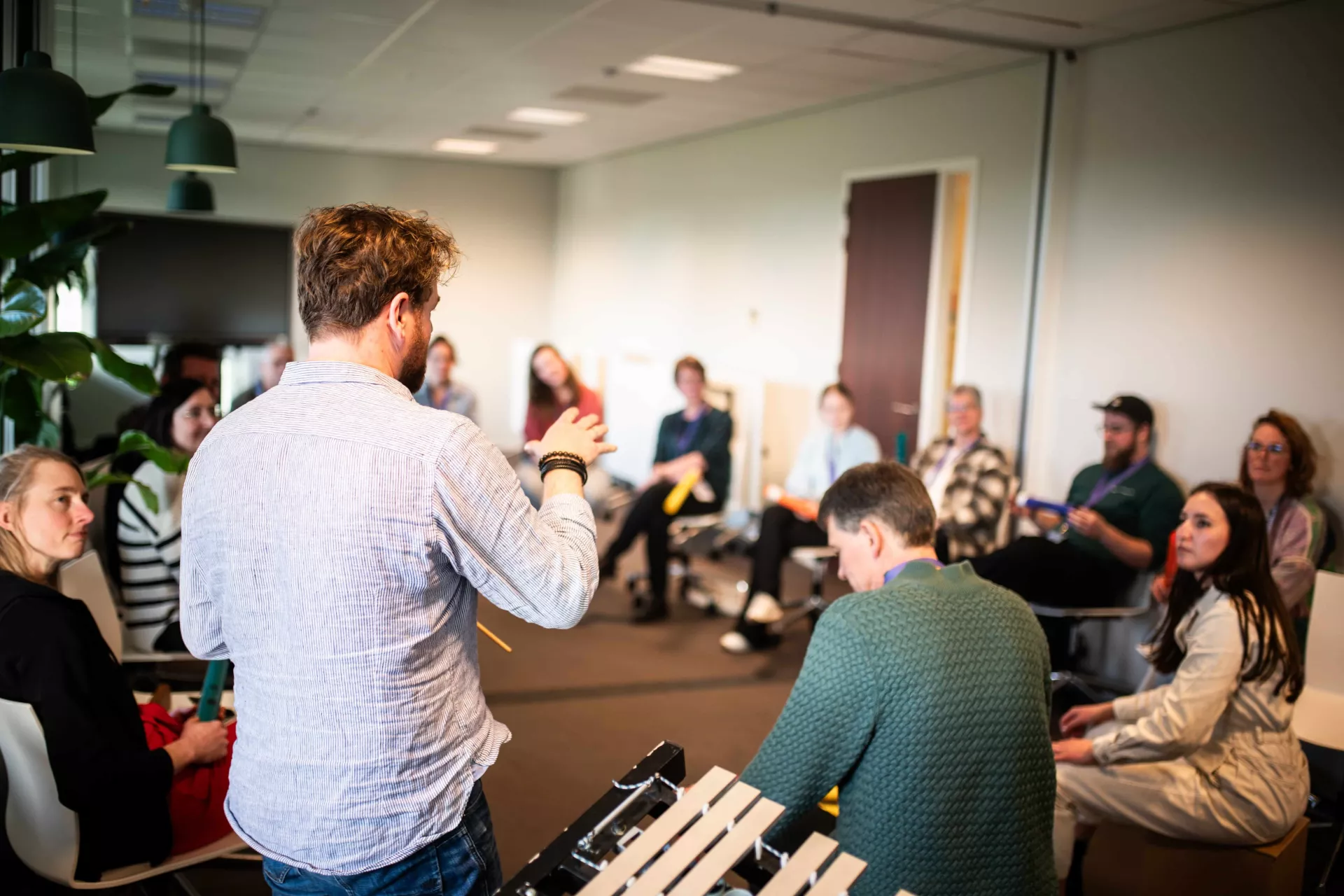 Een groep mensen in een kring tijdens een vergadering of workshop in een kantooromgeving.