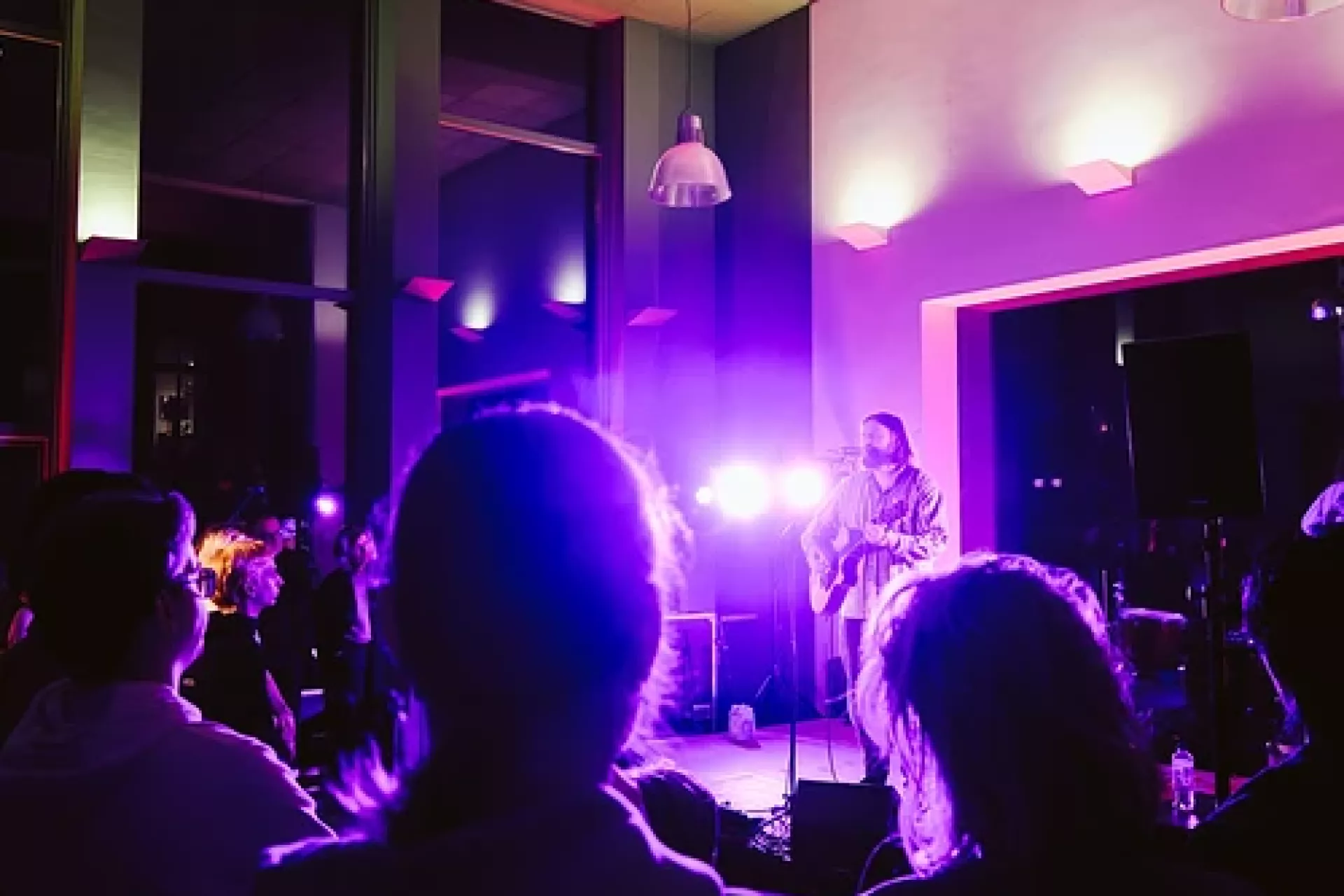 Een live muziekoptreden met publiek in een sfeervolle zaal.
