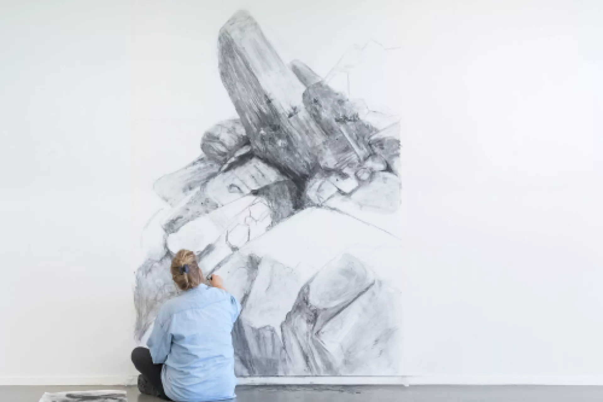 Een persoon tekent een grote zwart-wittekening op een muur.