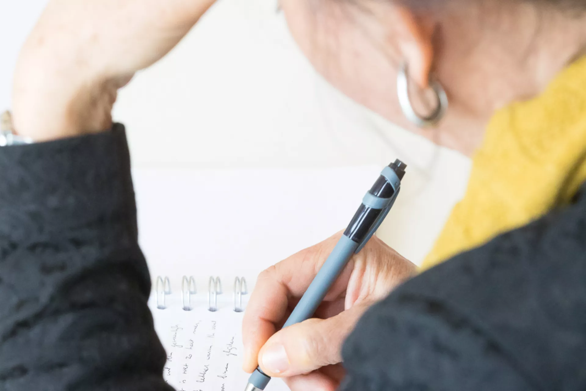 Je ziet een persoon en kijkt over haar schouder terwijl ze schrijft.