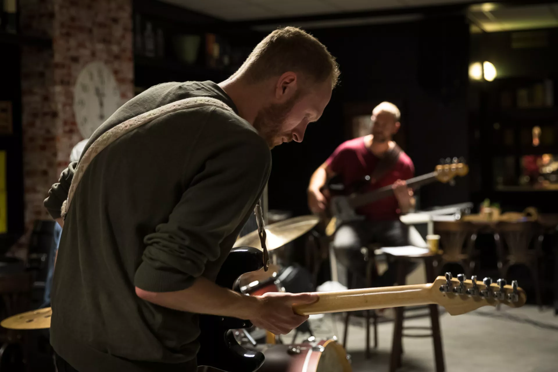 Twee muzikanten spelen elektrische gitaar in een sfeervolle ruimte.