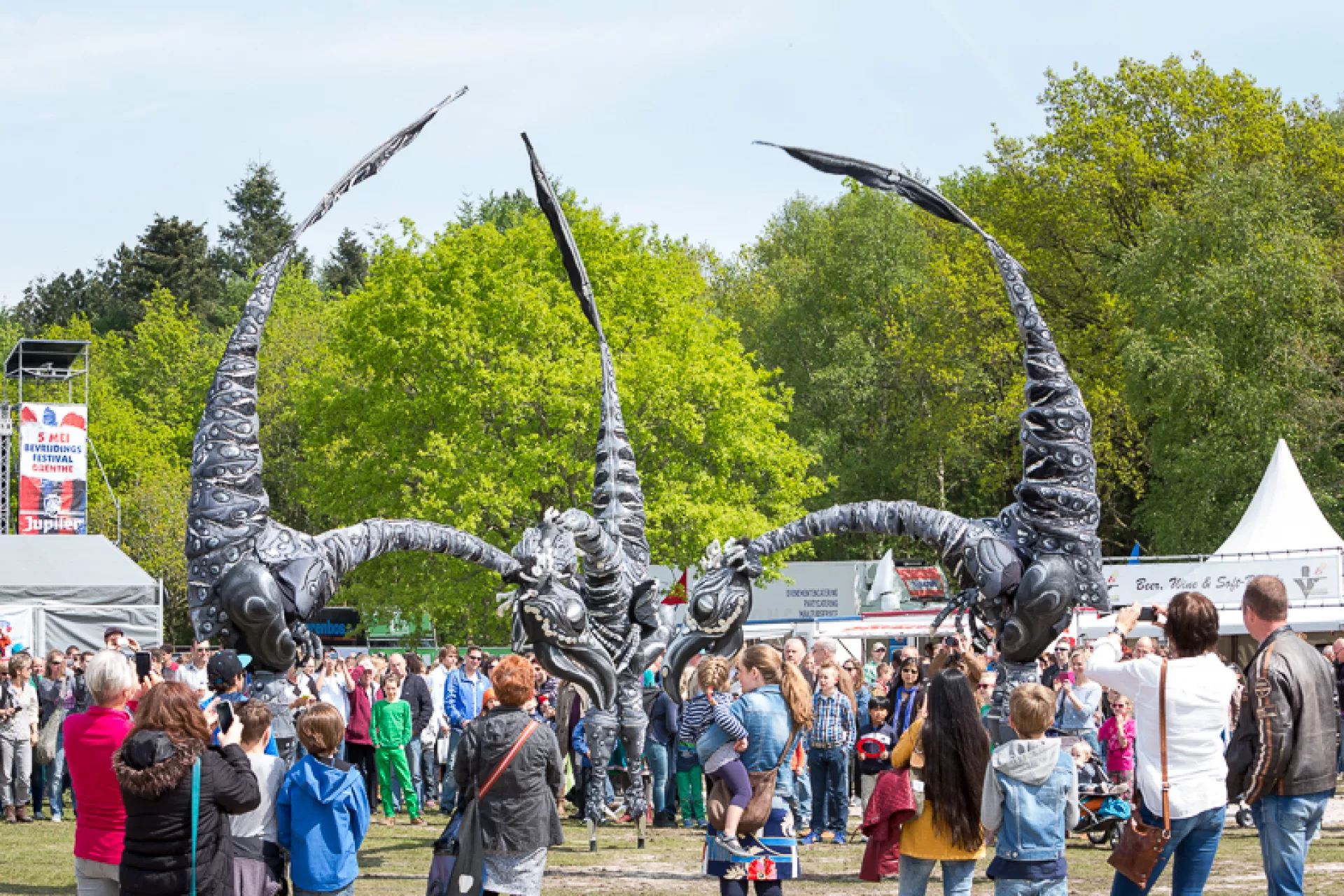 foto van een festival met heel veel publiek en een groot fantasiebeest met grote tentakels