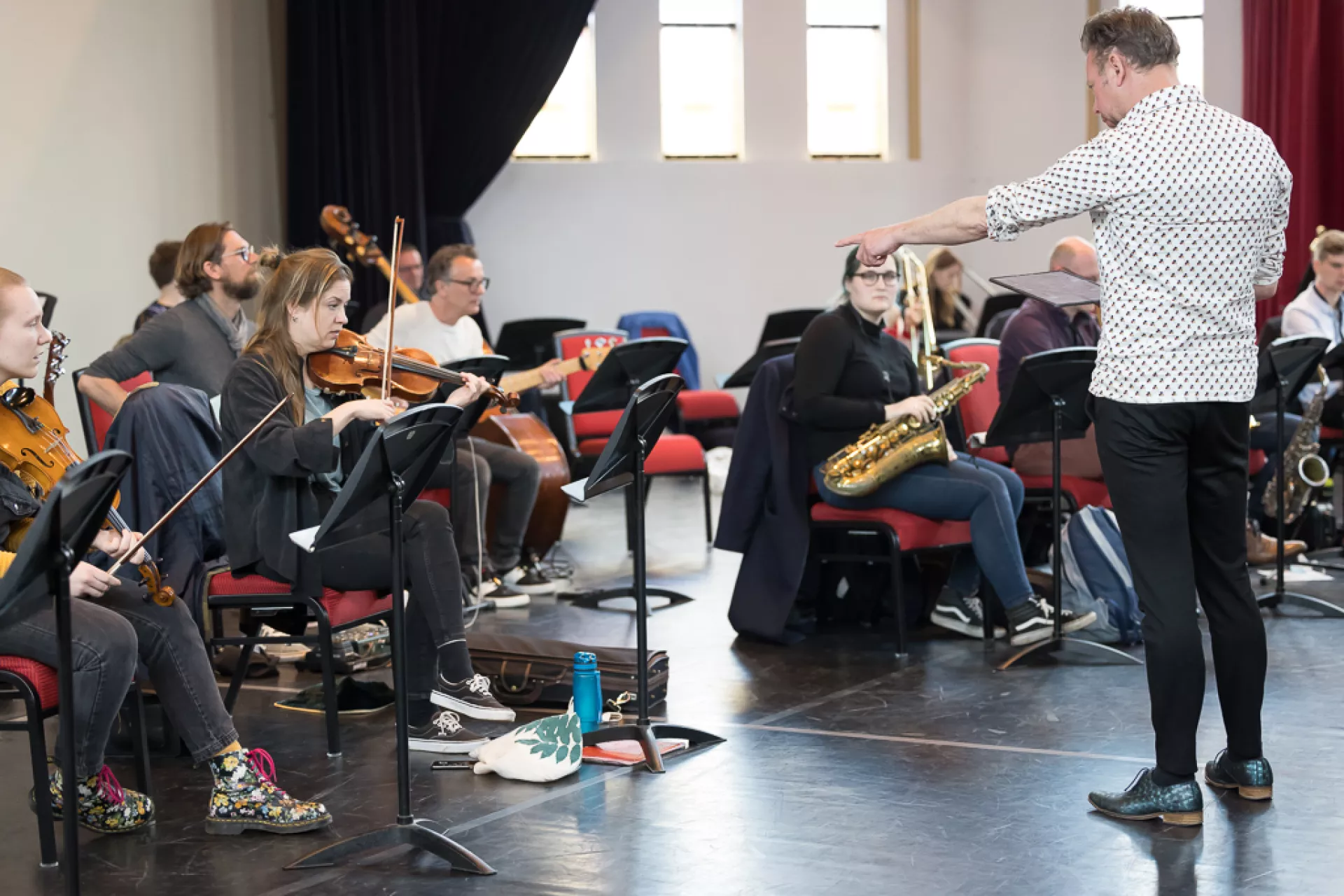 Muzikanten repeteren onder leiding van een dirigent.