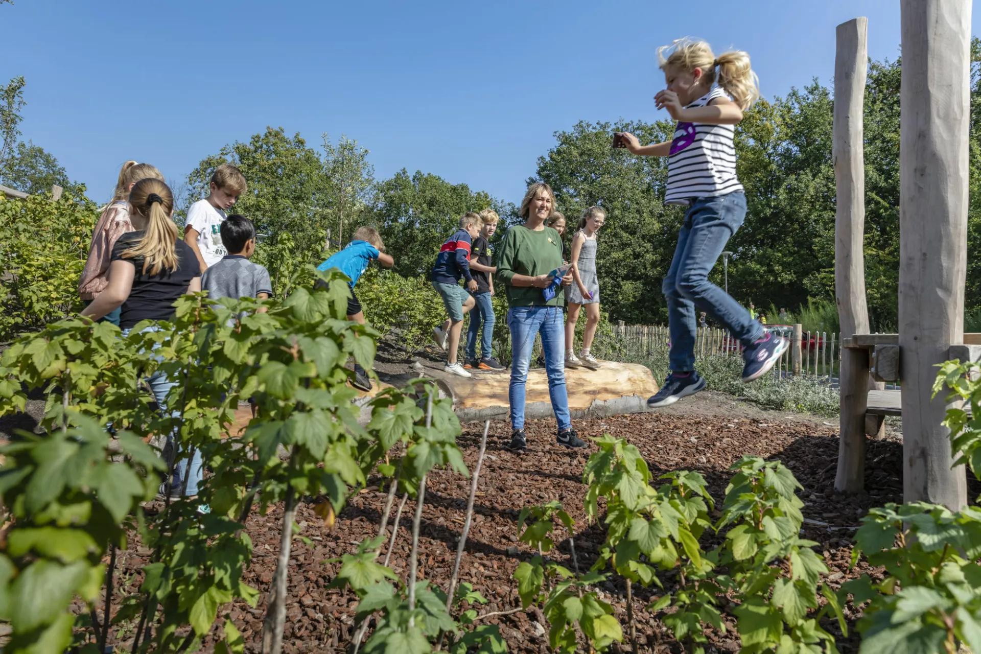 Het Buitenlokaal - Natuureducatie - Kind dat springt in een groene omgeving.